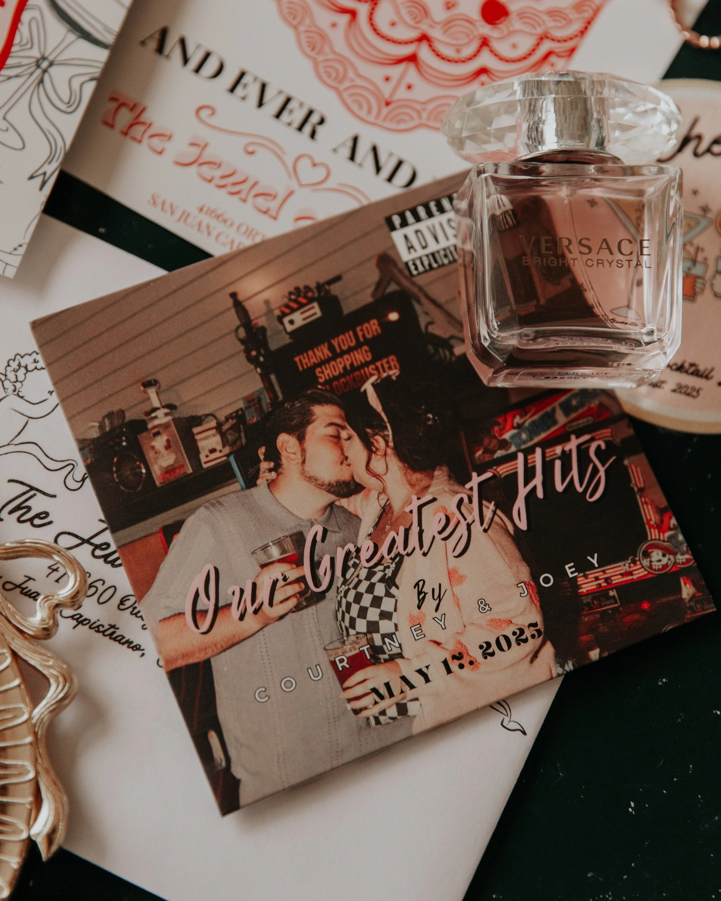 Wedding detail photo featuring perfume bottle, custom stationery, and framed couple portrait