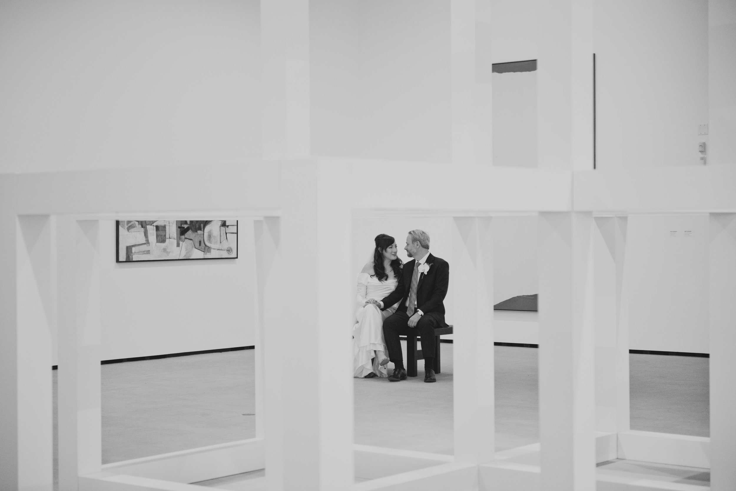 Bride and groom holding hands inside a modern art museum after their wedding ceremony.