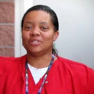 Portrait of a woman with dark hair wearing a red top and a lanyard.