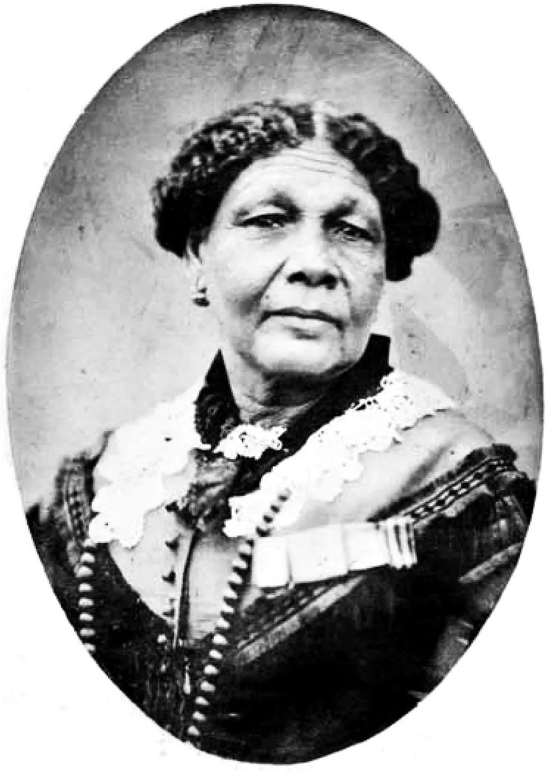 Black and white portrait of an elderly woman wearing traditional clothing and jewelry, with a serious expression.