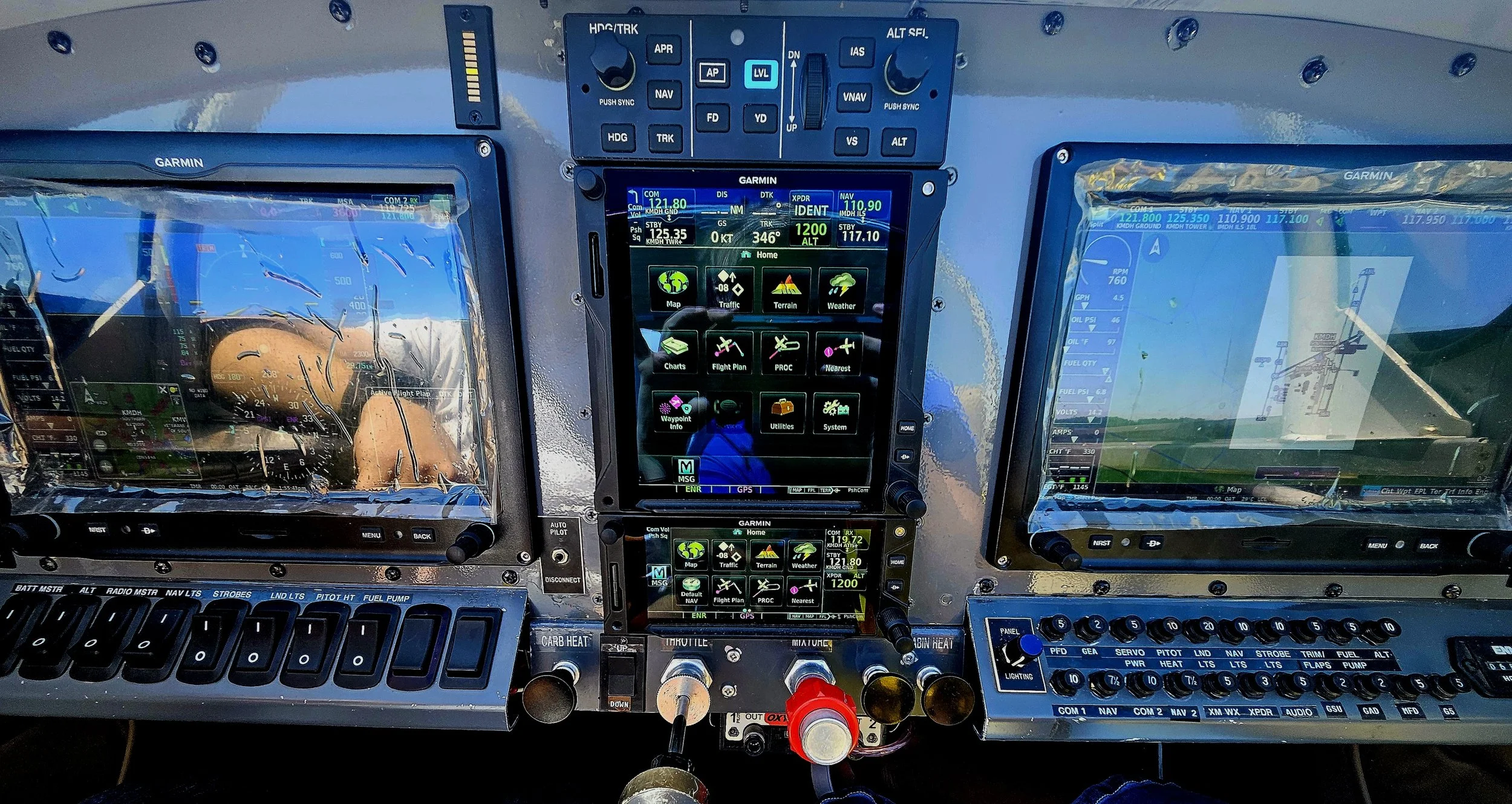 Cockpit avionics with multiple Garmin screens displaying navigation, weather, and flight data.