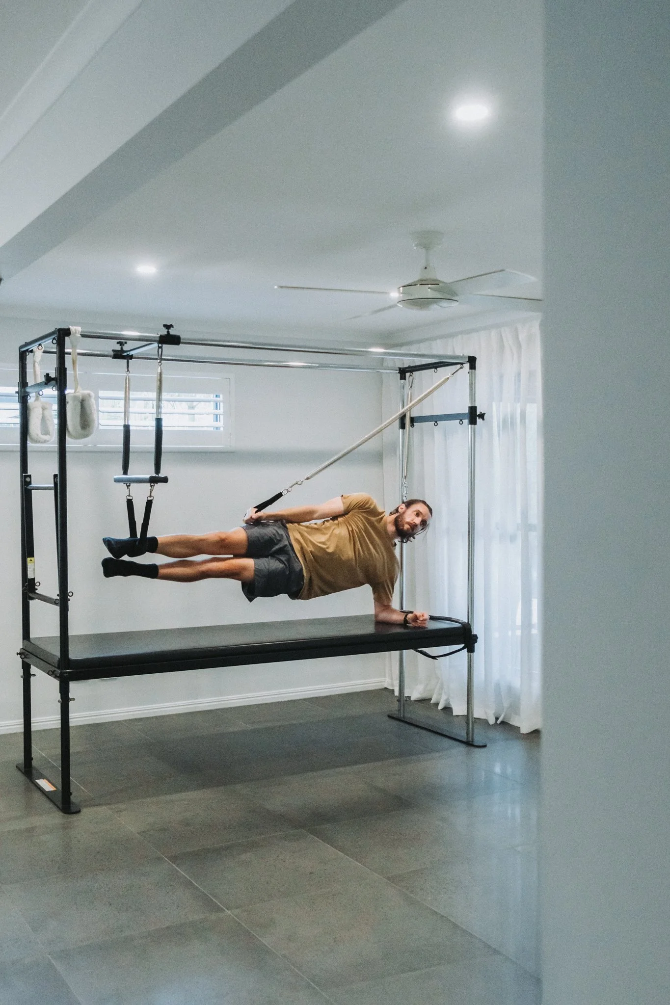 A male client in an impressive side plank based hovered hold in straps