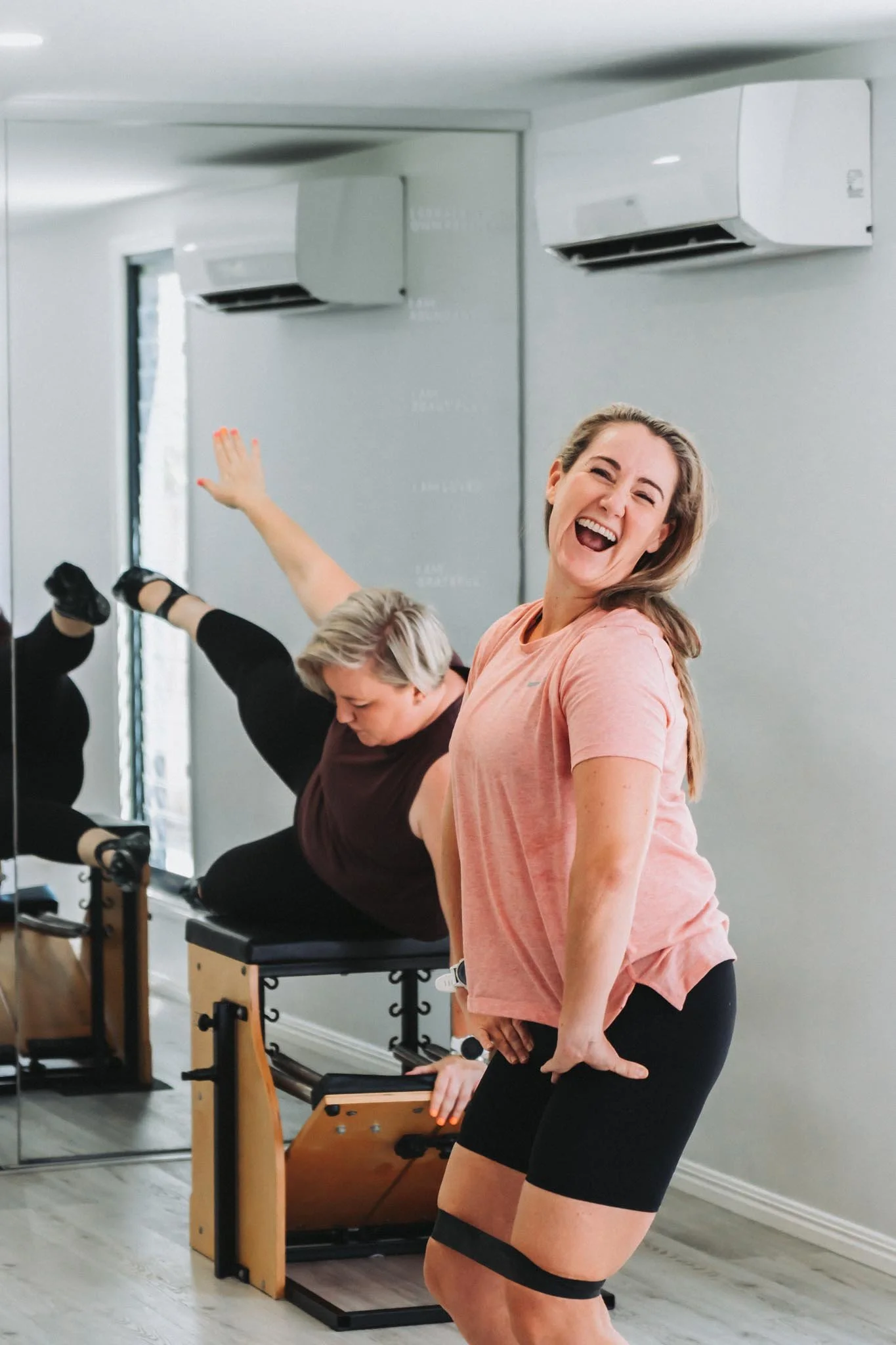 Two beautiful Mums working out side by side, goofing around laughing