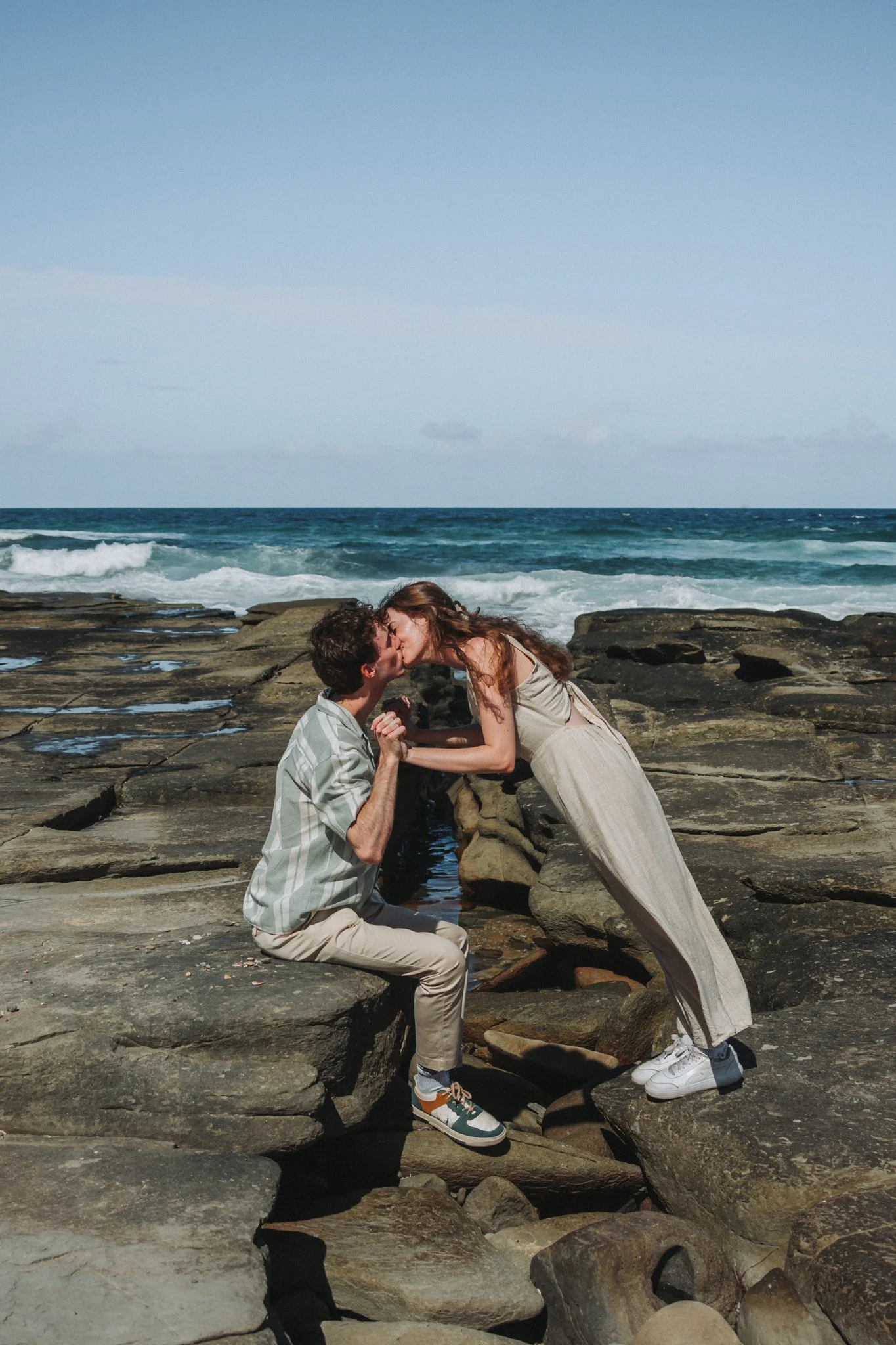 Young, newly engaged couple plying in the rock pools of Point Cartwright