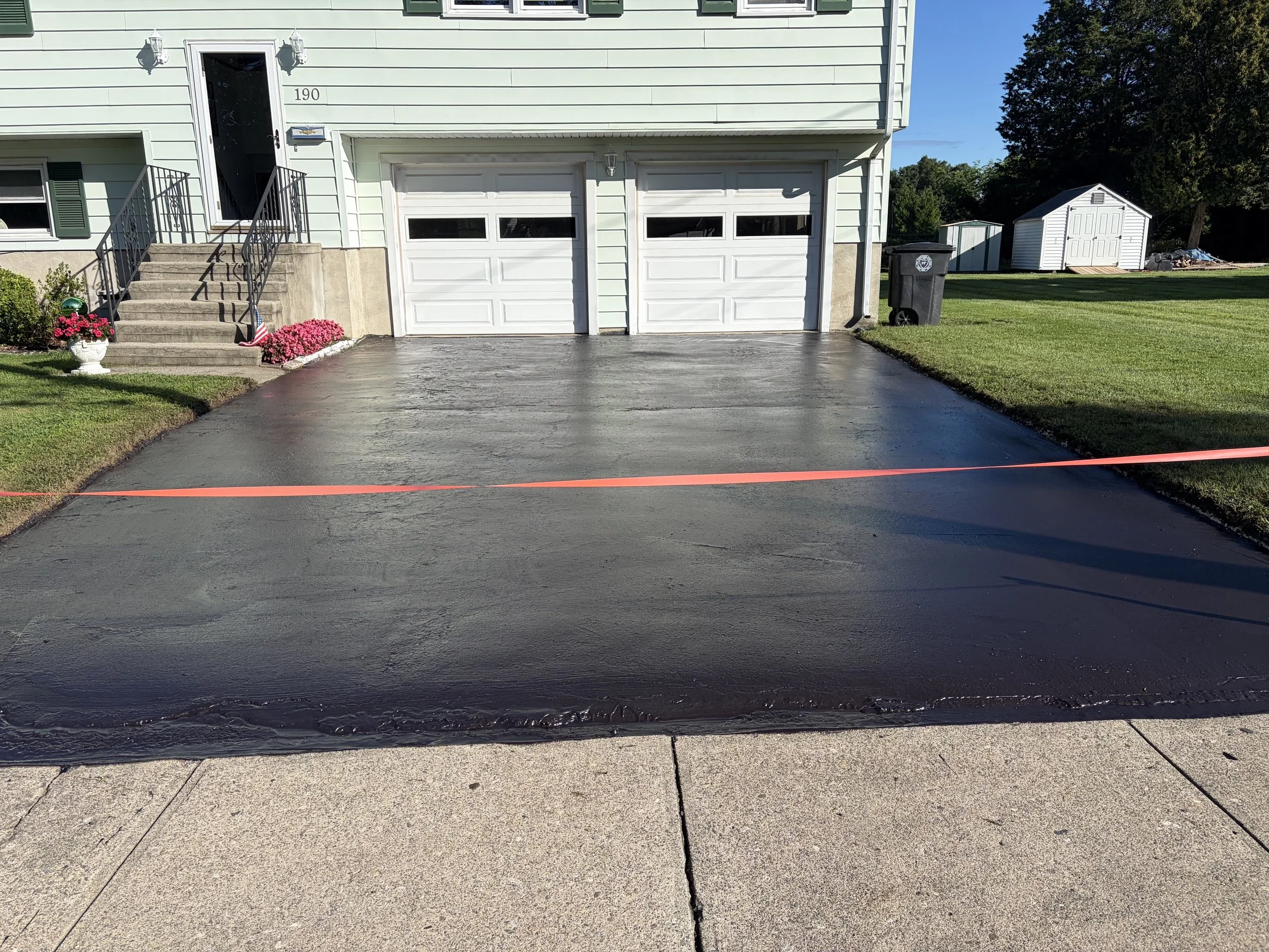 A new layer of sealcoating gives this Milford, CT driveway a brand-new glossy look.