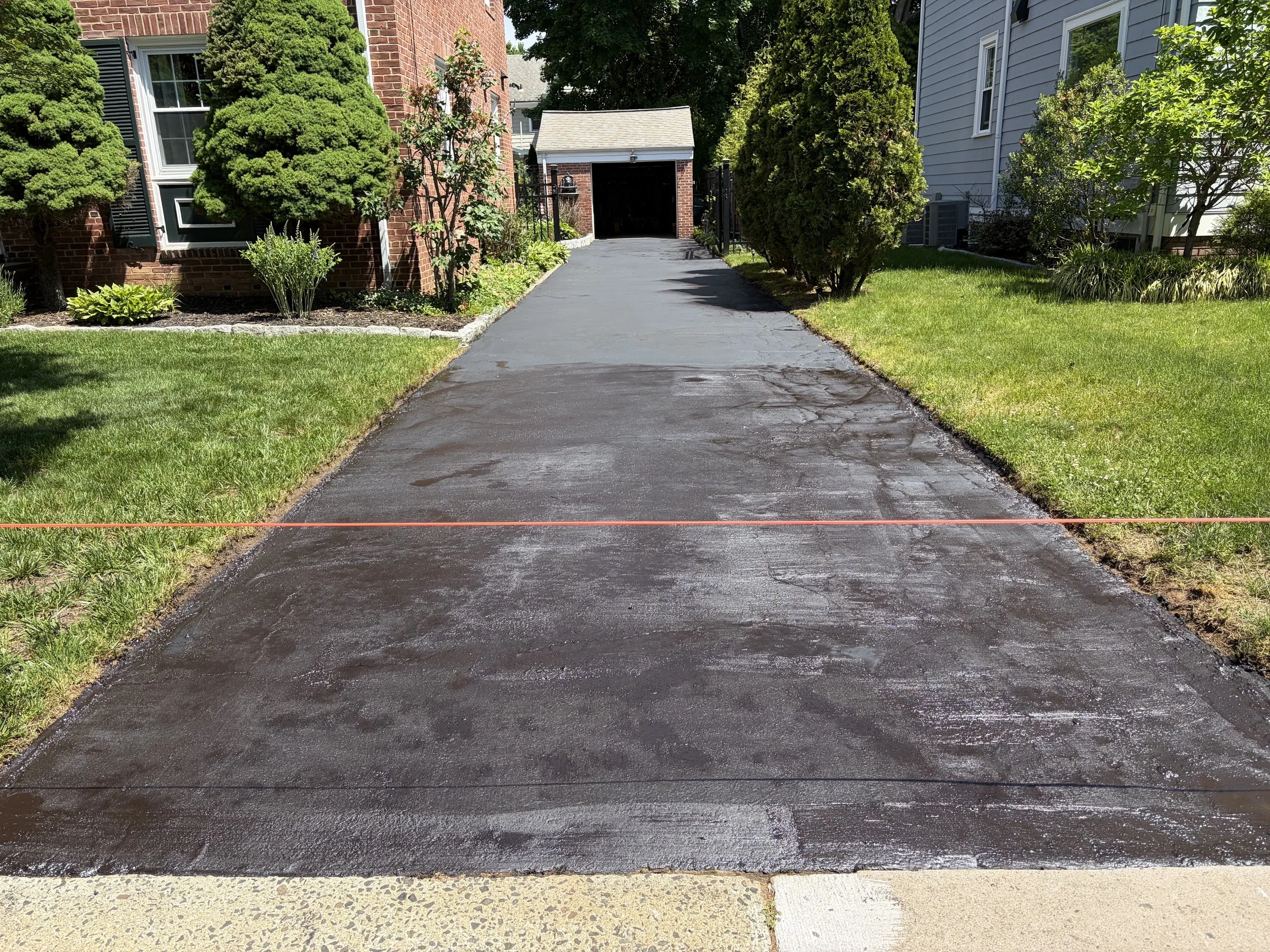 Freshly sealcoated residential asphalt driveway in New Haven, featuring a smooth black finish, clean edges, and enhanced curb appeal by Five Star Complete Asphalt Services on May 22, 2026.