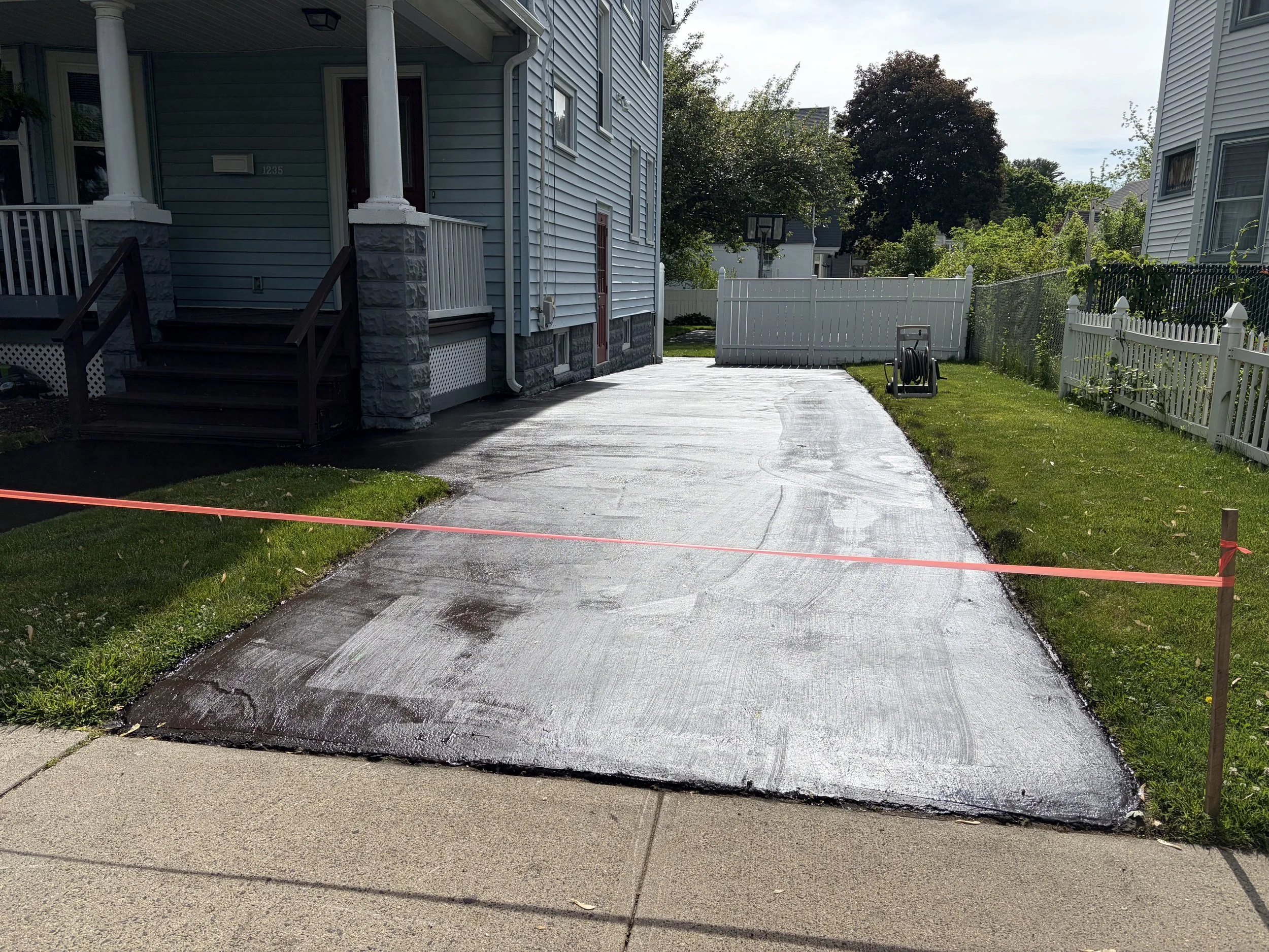 Freshly sealcoated residential asphalt driveway is seen in New Haven, featuring a smooth black finish and clean edges completed by Five Star Complete Asphalt Services on May 22, 2026.