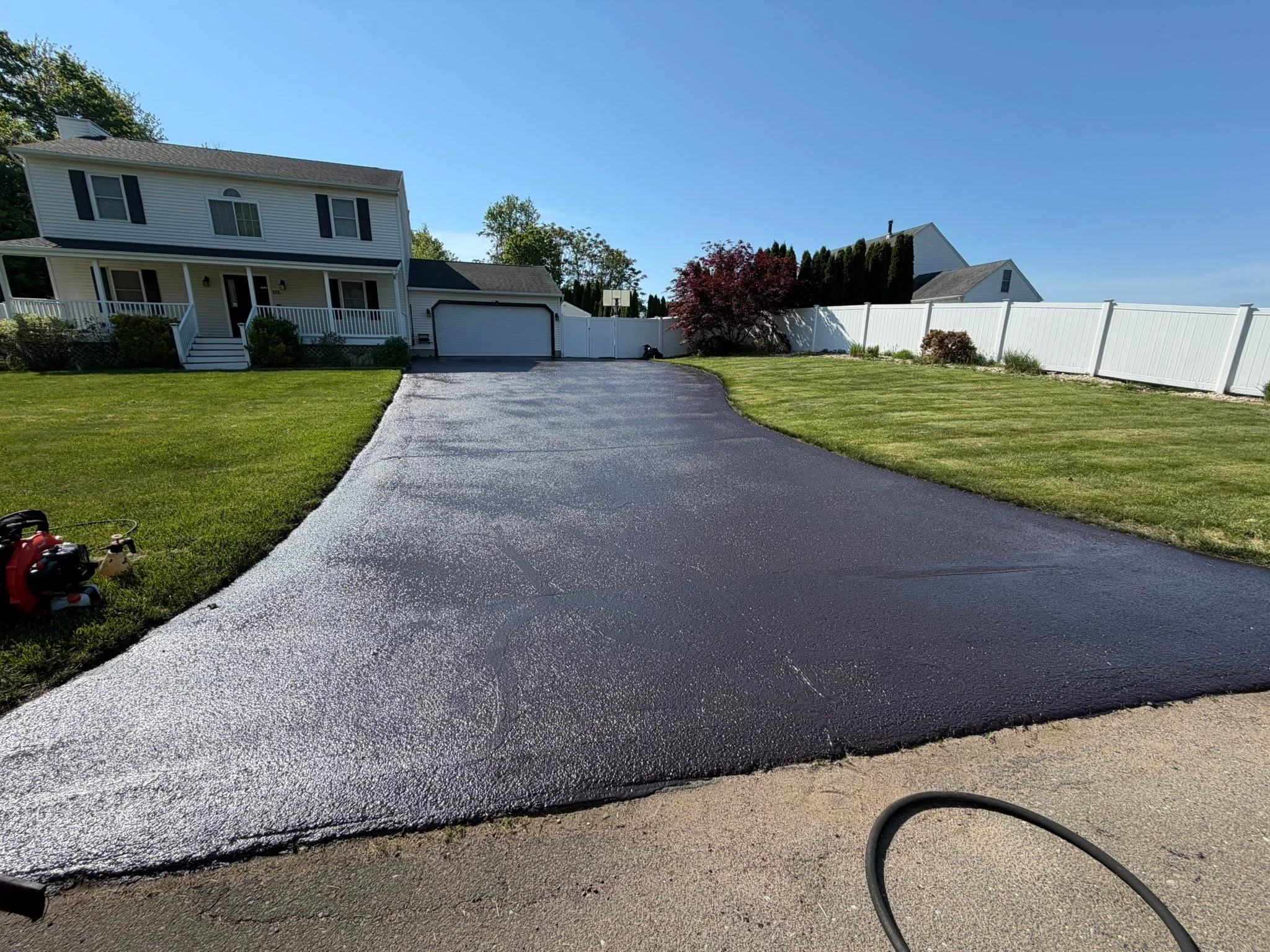 Freshly sealcoated residential asphalt driveway with completed asphalt repair work by Five Star Complete Asphalt Services in East Haven, Connecticut, featuring a smooth black finish and clean curb appeal.