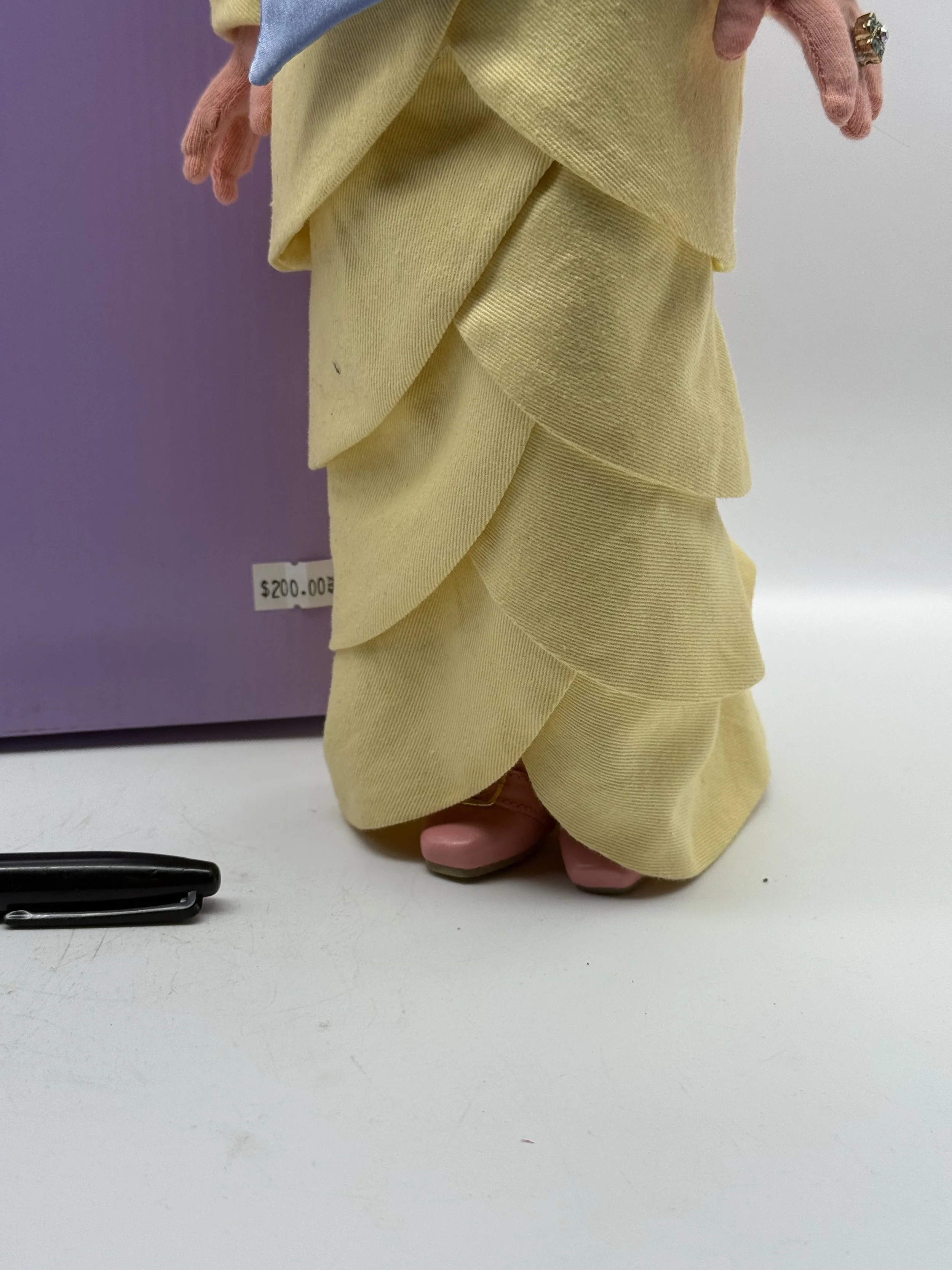 Hem of the My Fair Piggy doll's tiered yellow gown, marker for scale