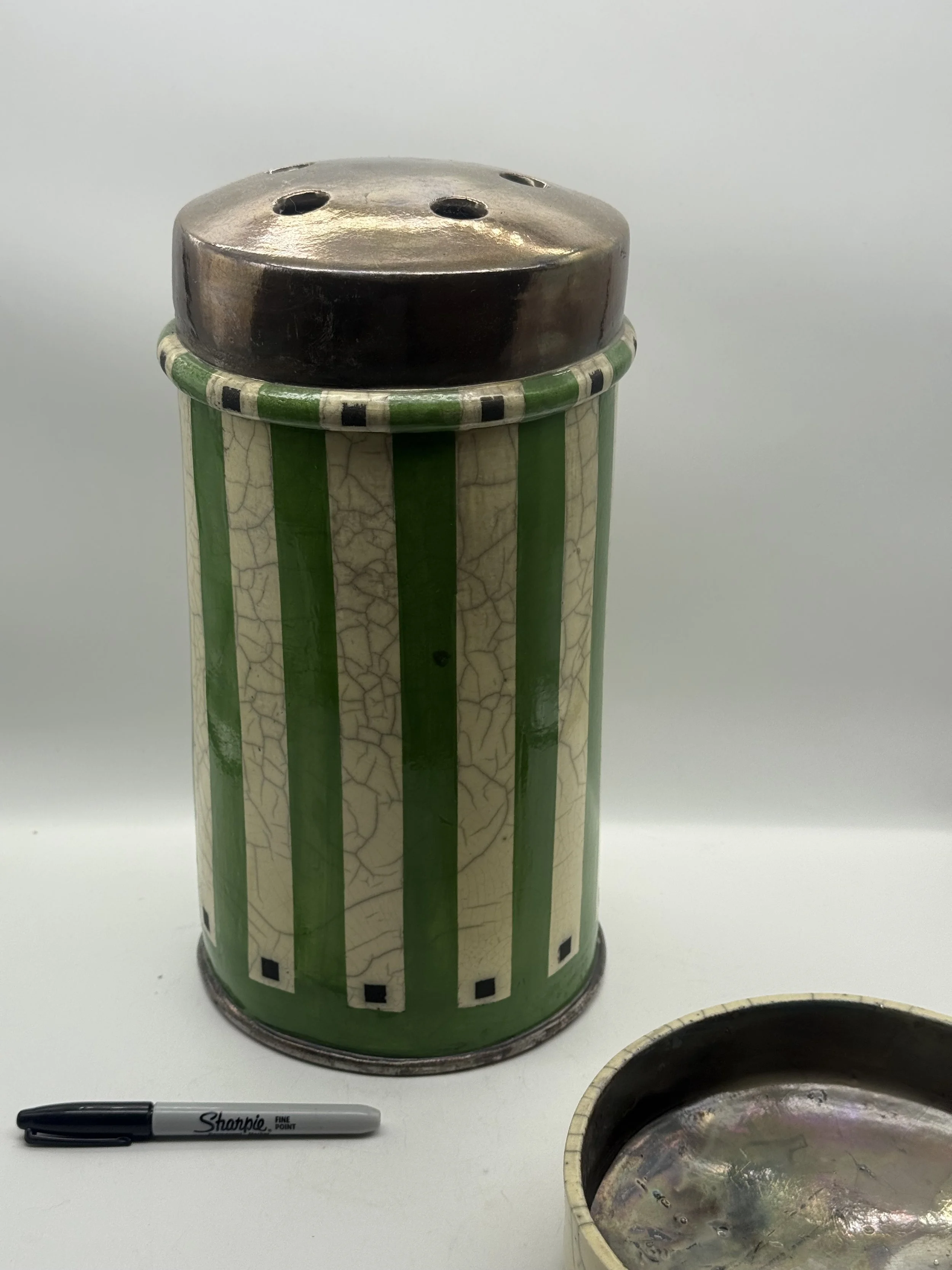 Karen Shapiro raku Mennen talcum from the striped side, lid beside it