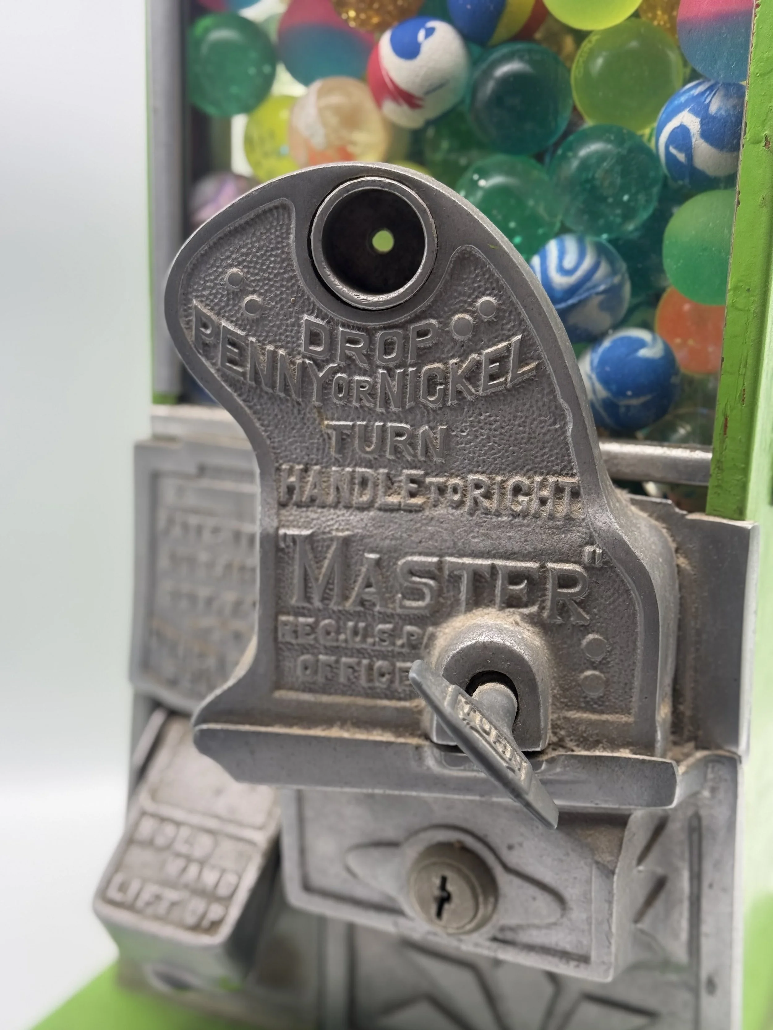 Close-up of the chrome Master coin mechanism on the gumball machine