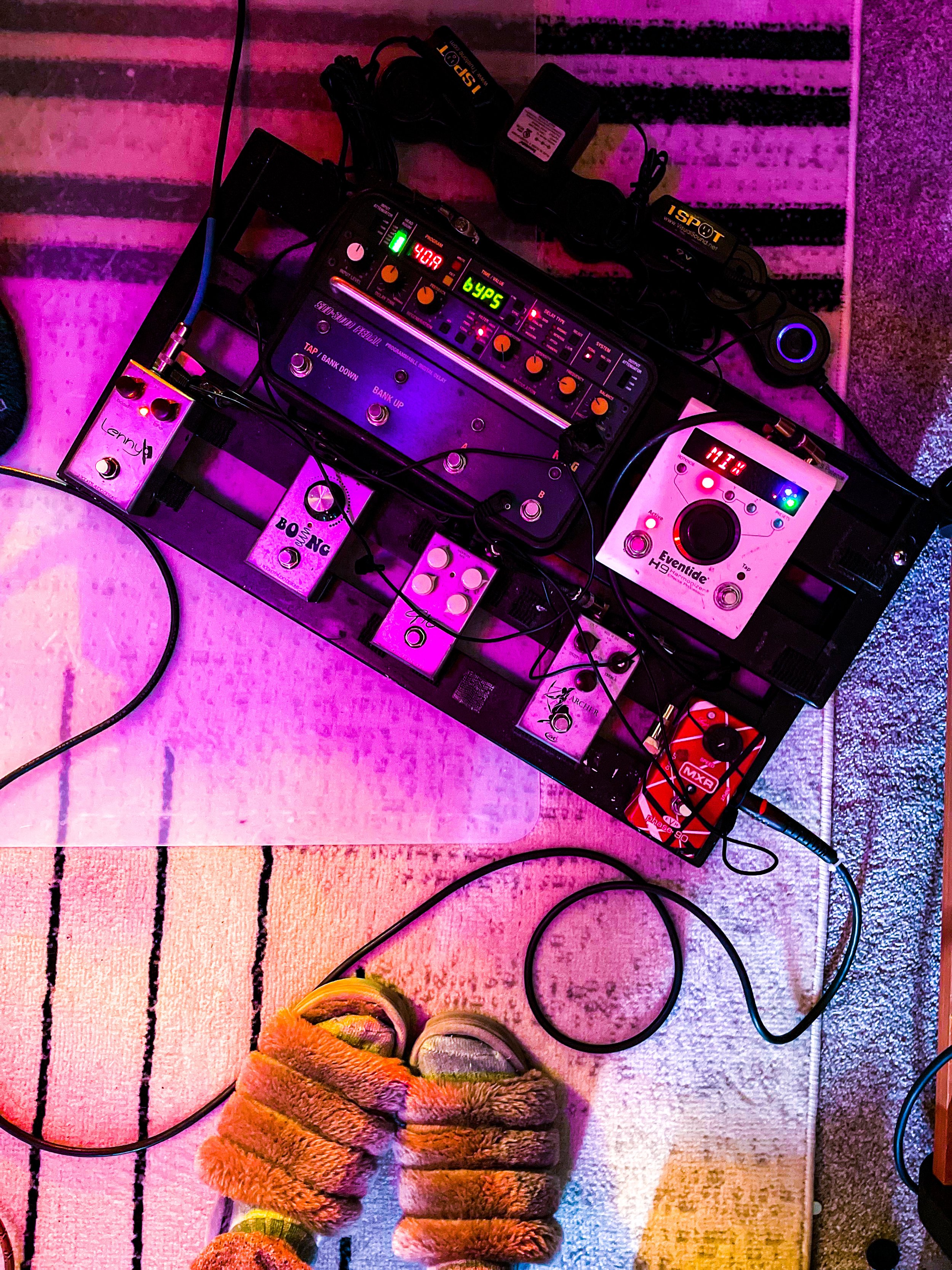 Kira Violet in slippers in front of a pedal with colored lights at The Noise Room.JPG