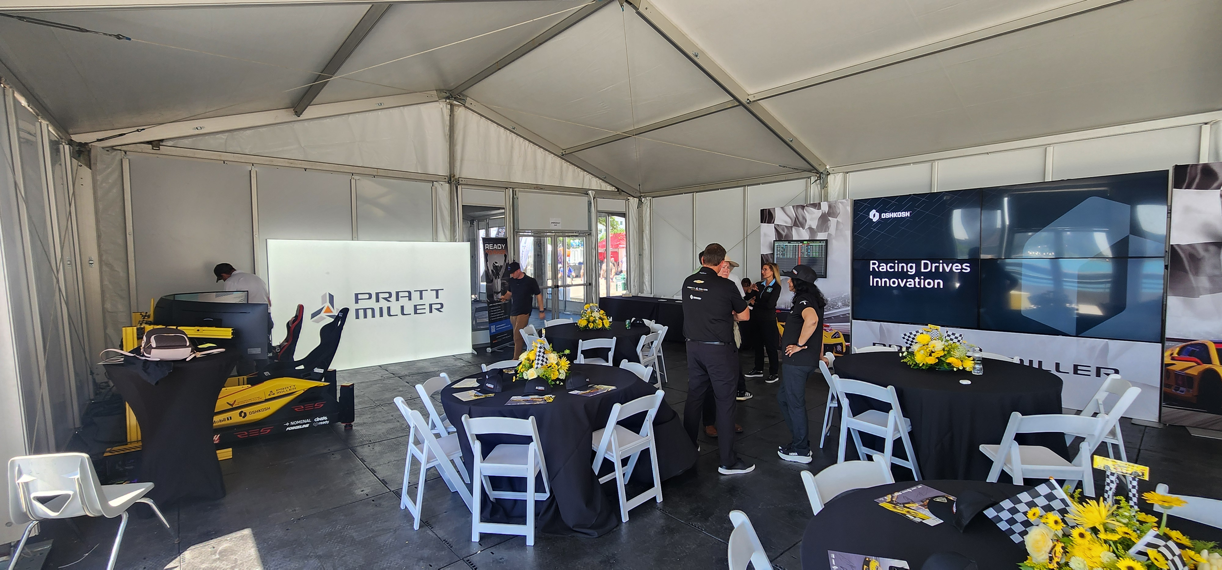 Hospitality tent setup at Detroit Grand Prix with black cloth round tables and white folding chairs under hard-side white tent