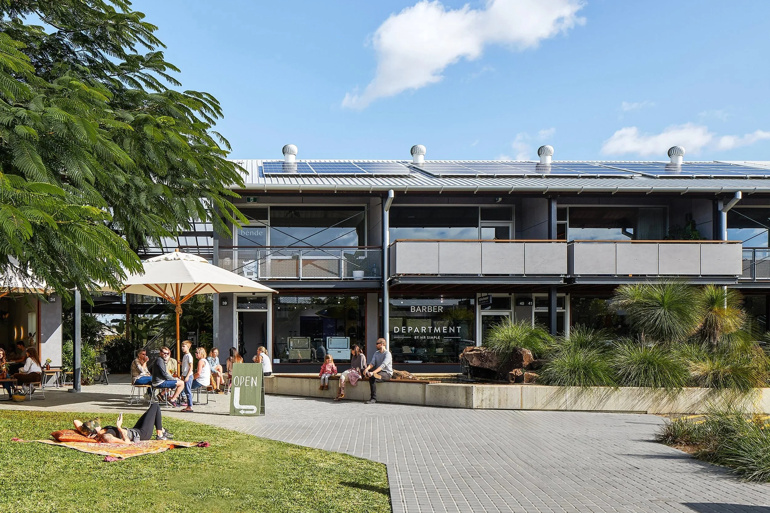 large balconies overlooking the main courtyard at Habitat Byron Bay. People are sat under parasols enjoying coffee