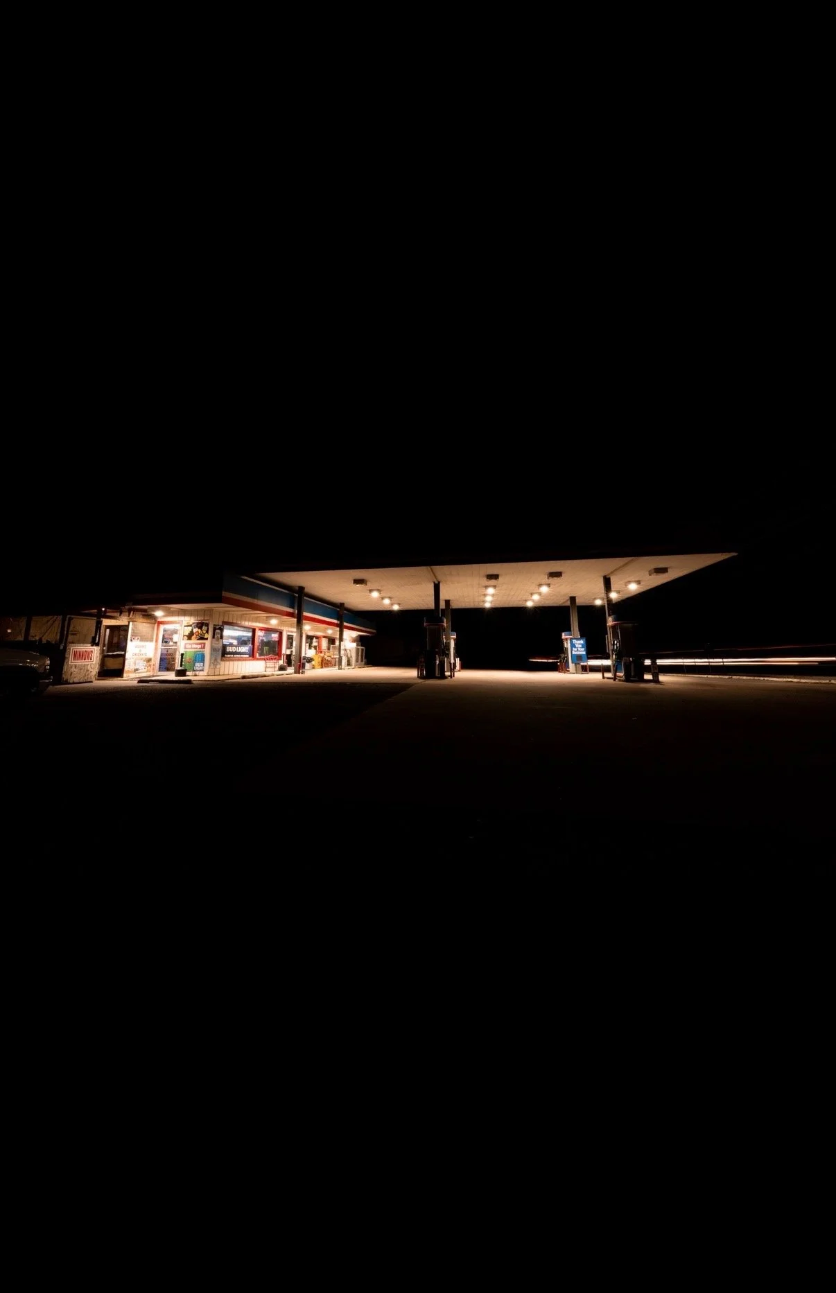 An empty gas station illuminated with bright lights at night.