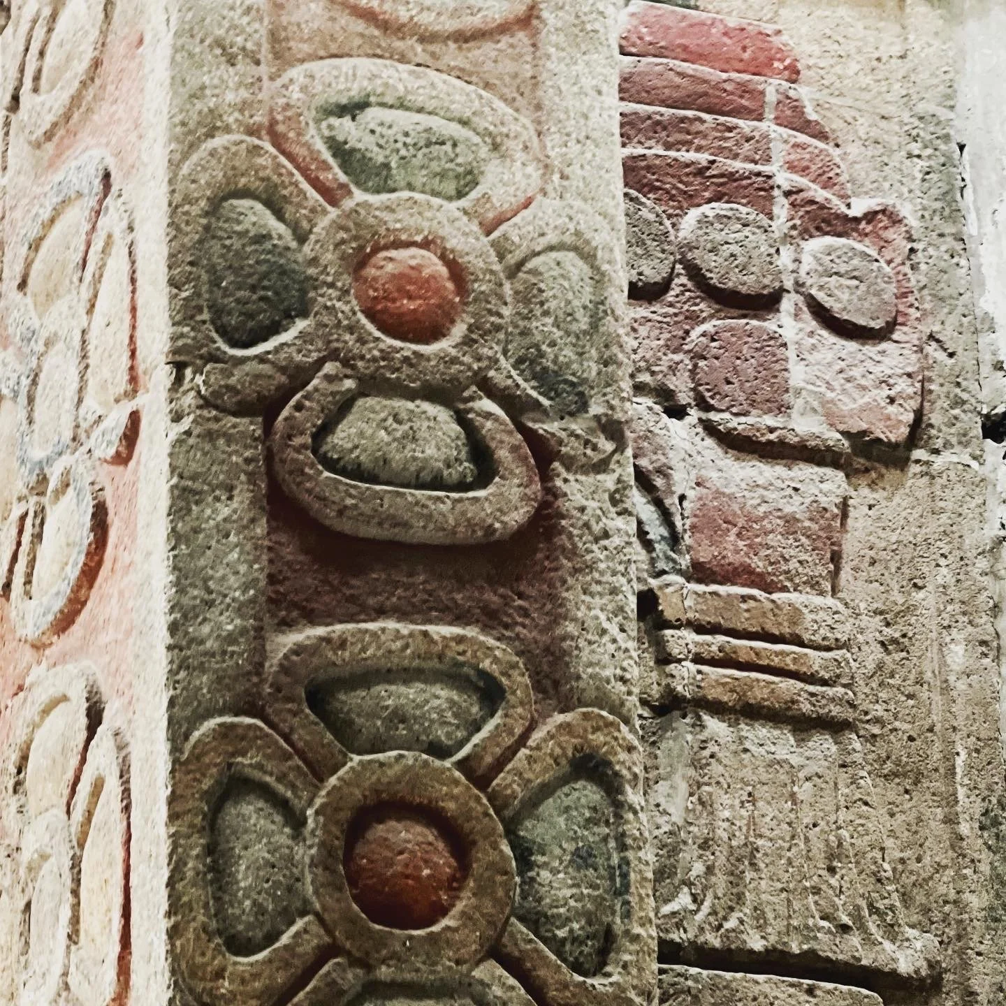 Close-up of ancient stone carvings with geometric and floral patterns on a brick wall.
