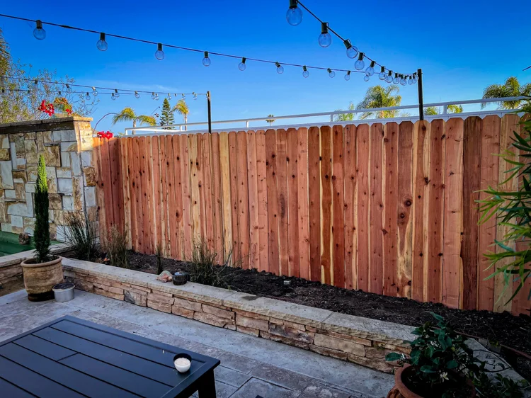 Wood dog ear fence installed along a backyard patio