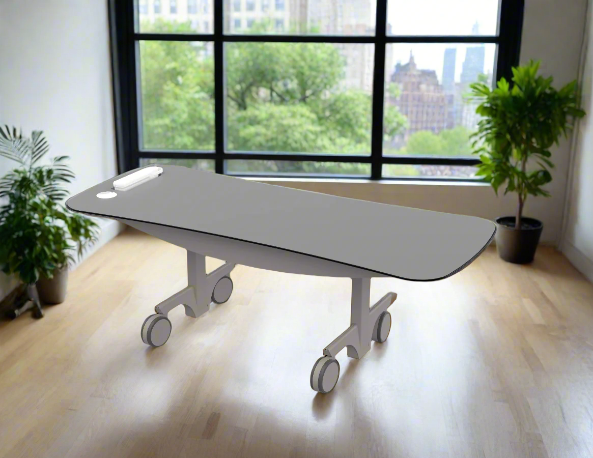 A modern medical or examination table with wheels in a bright room with large windows and green plants.