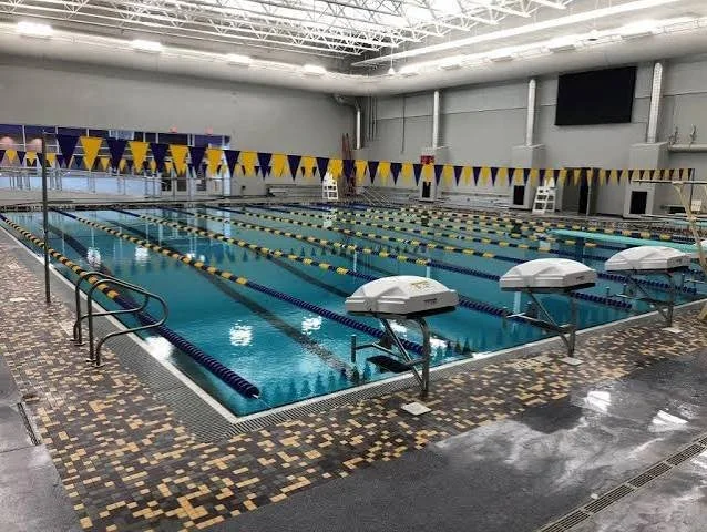 Inside an indoor swimming pool with lane markers and a banner on the wall that reads 'Swim Parents'.