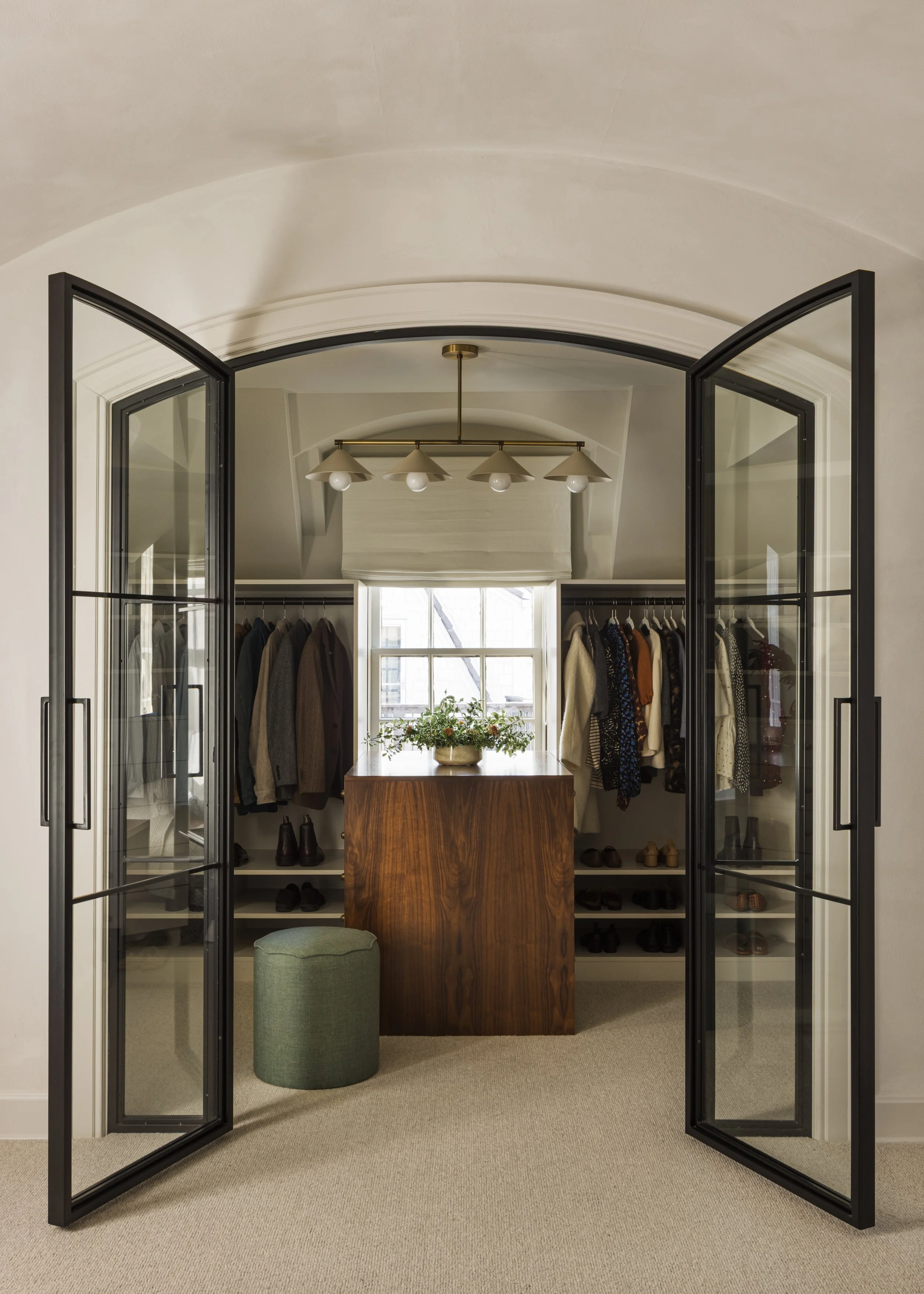 Glass partitioned iron French doors connect the closet to the bedroom, making both spaces feel bigger, a trade off from seeing your partners shoes on the floor while lying in bed. 