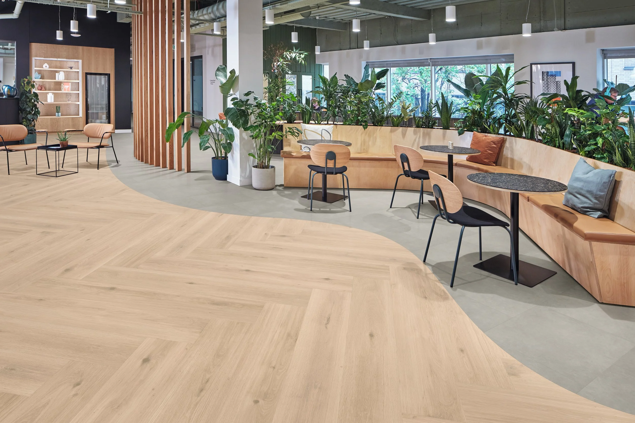 Modern living room with white sofa, black chairs, wall-mounted TV, green accents, large windows, wooden flooring, and artwork on the wall.