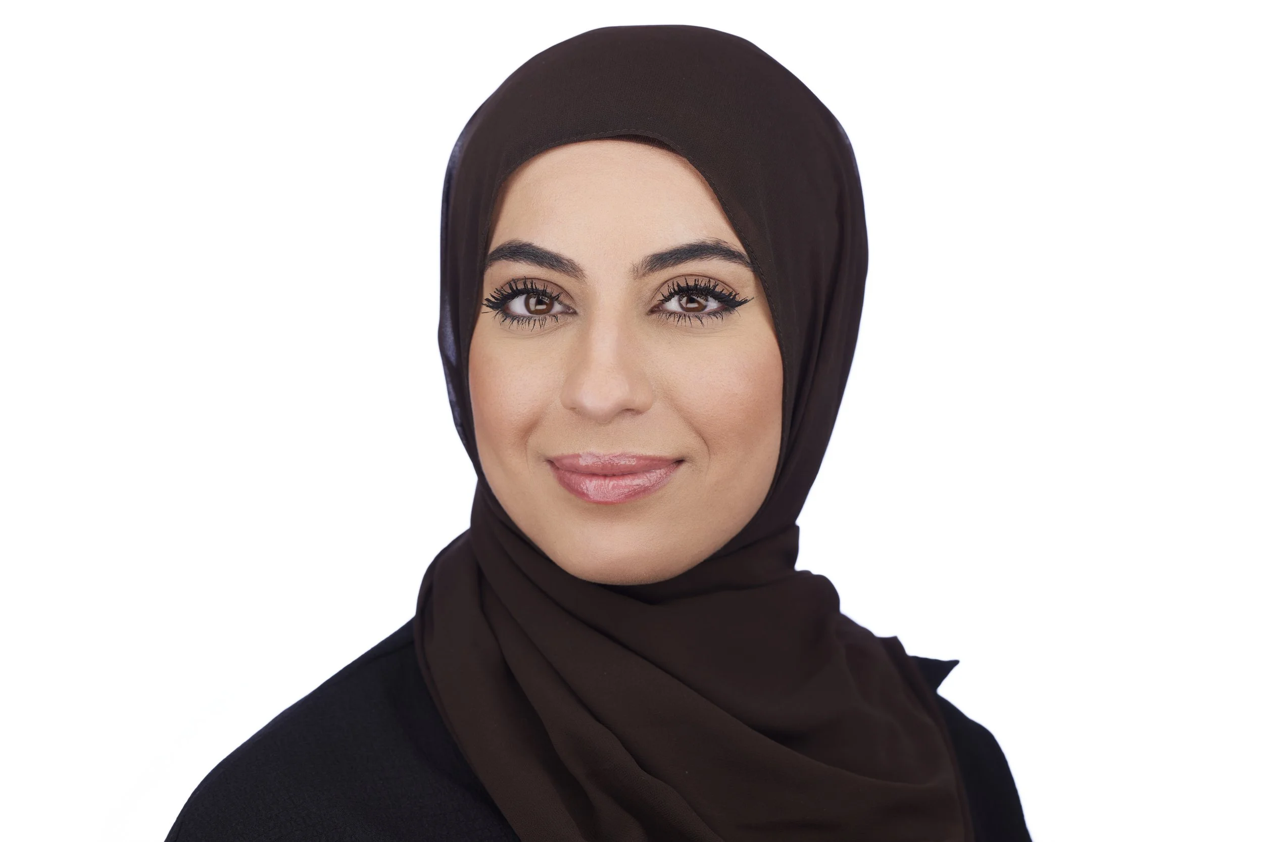 Corporate headshot portrait of a woman wearing a black hijab against a white background.