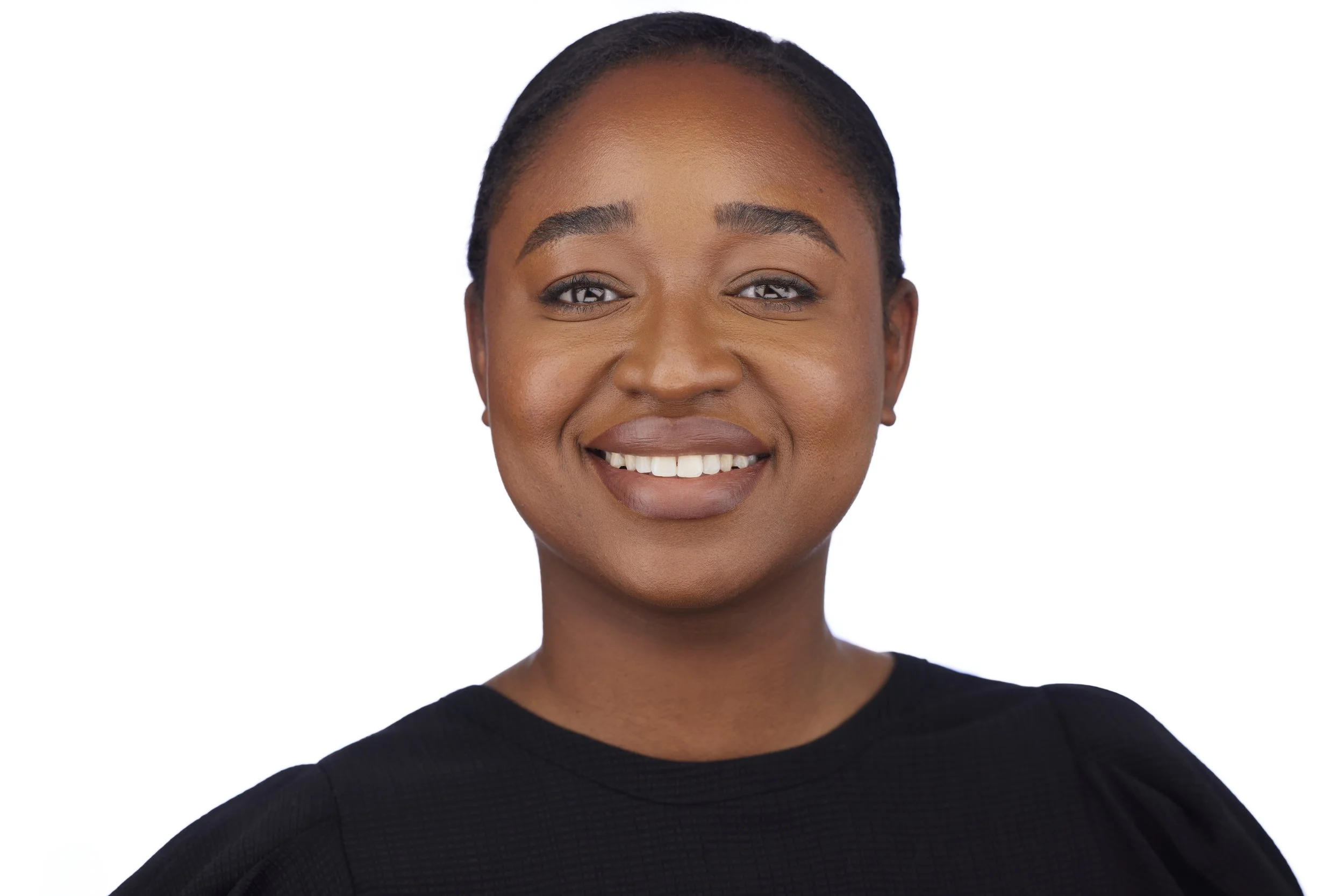 Corporate headshot of a black woman with short braided hair, wearing a black top, against a white background.