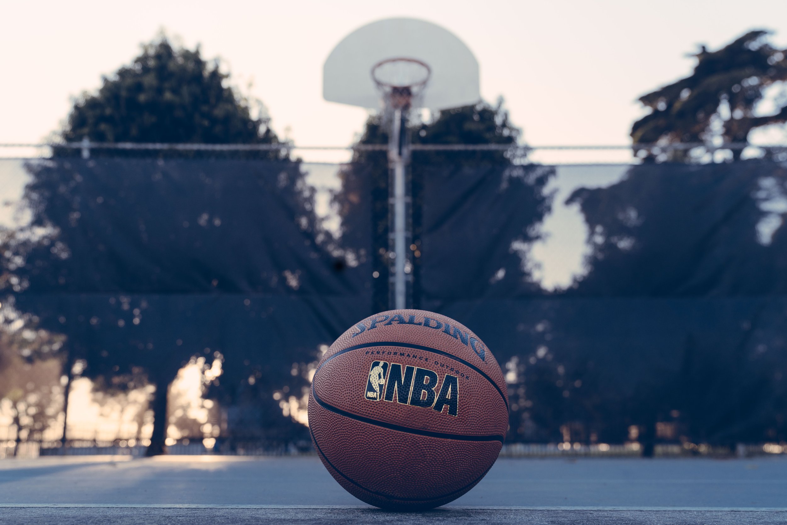 Basketplan med en basketboll i förgrunden och en basketkorg i bakgrunden.