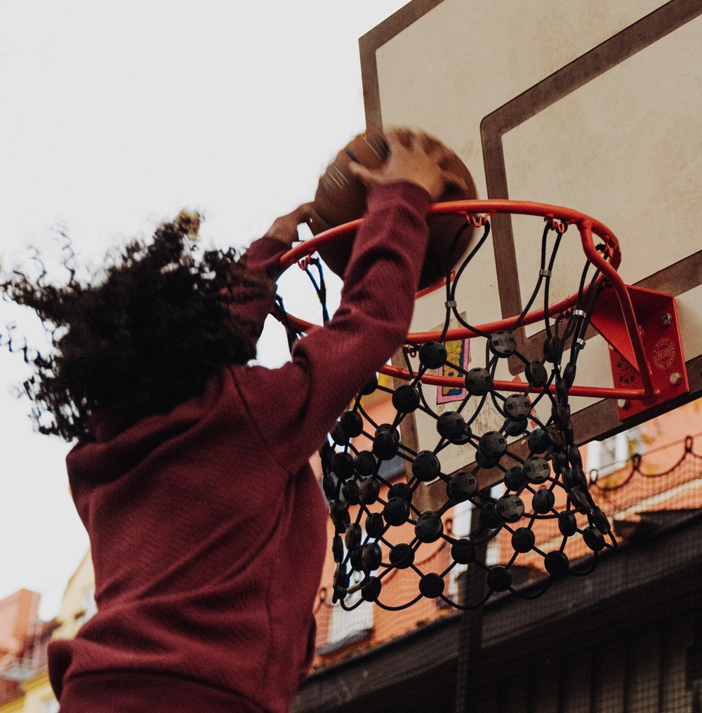 Barn med lockigt hår som spelar basket