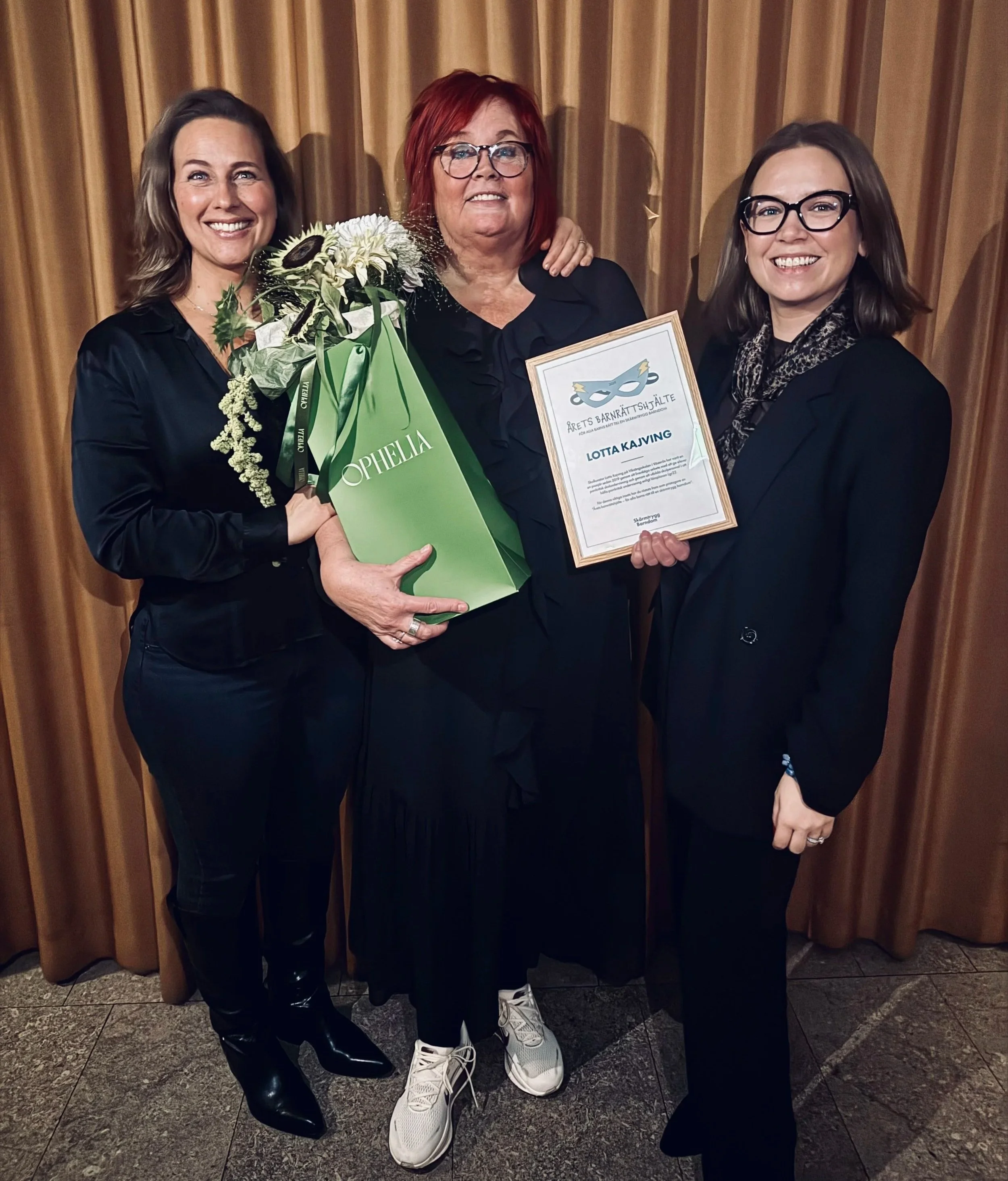 Skolkurator Lotta Kajving från Västerås ler och visar upp sitt diplom för priset Årets Barnrättshjälte 2025 på Viksängsskolan.