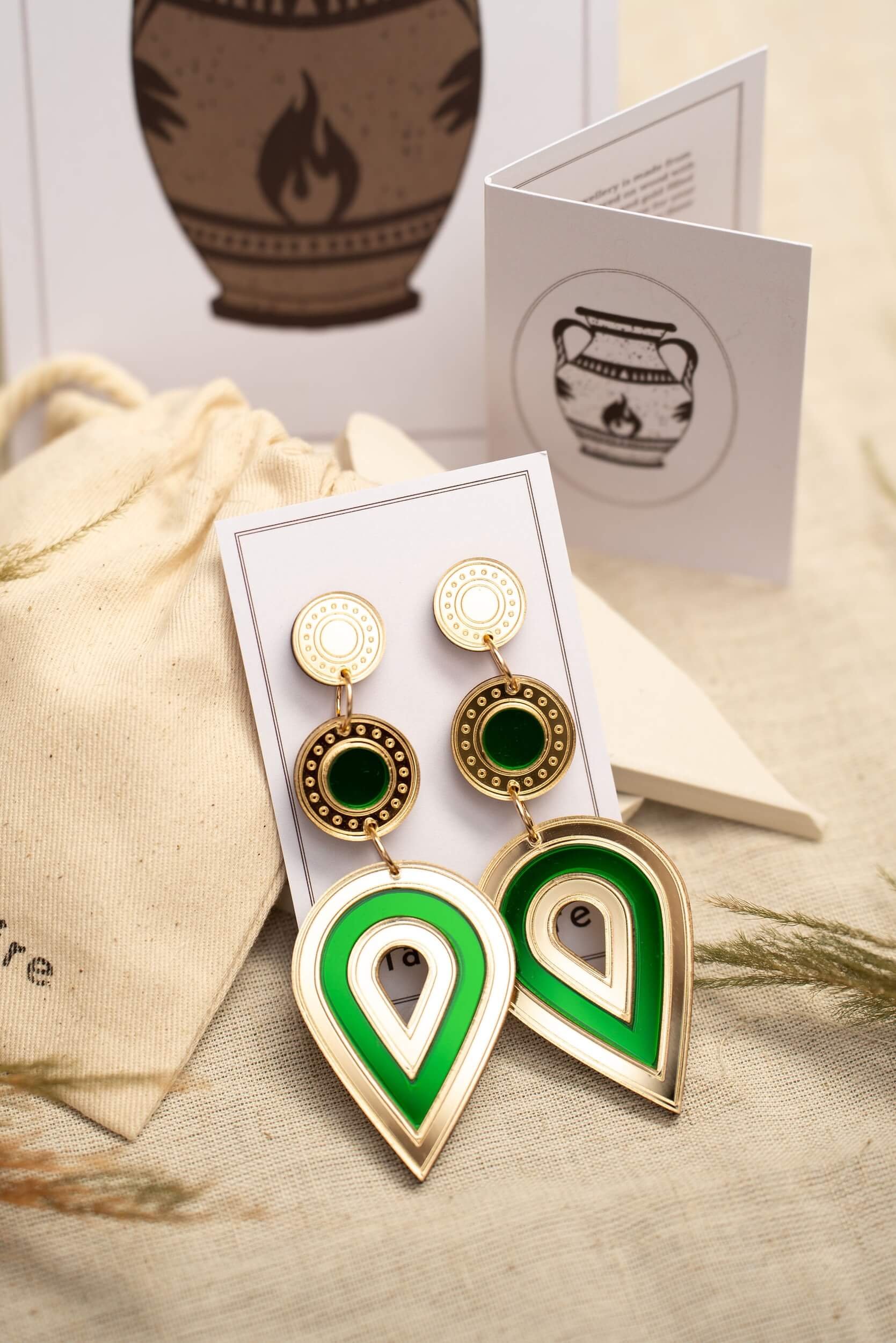 laser-cut acrylic teardrop statement earrings in mirror gold and emerald green on a backing card