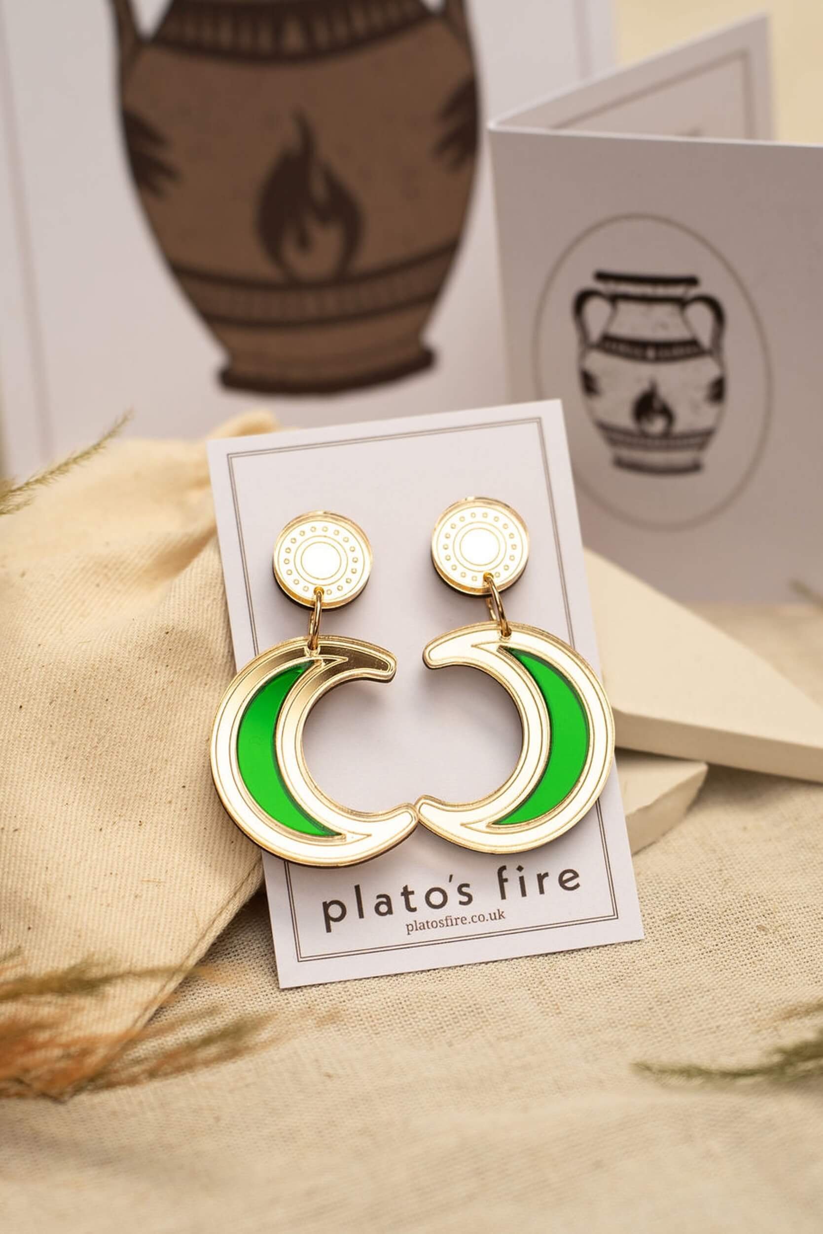 laser-cut acrylic crescent moon drop stud earrings in mirror gold and emerald green on a backing card