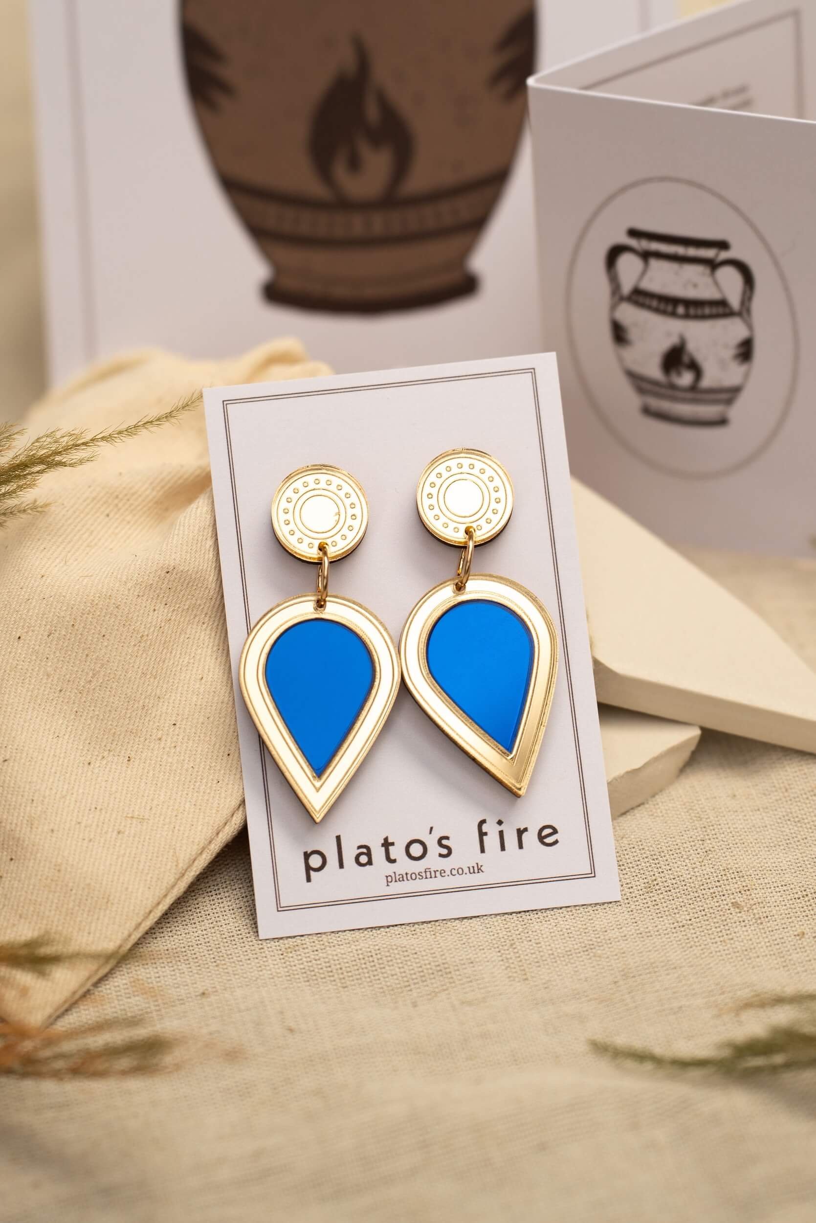 laser-cut acrylic teardrop drop stud earrings in mirror gold and royal blue on a backing card