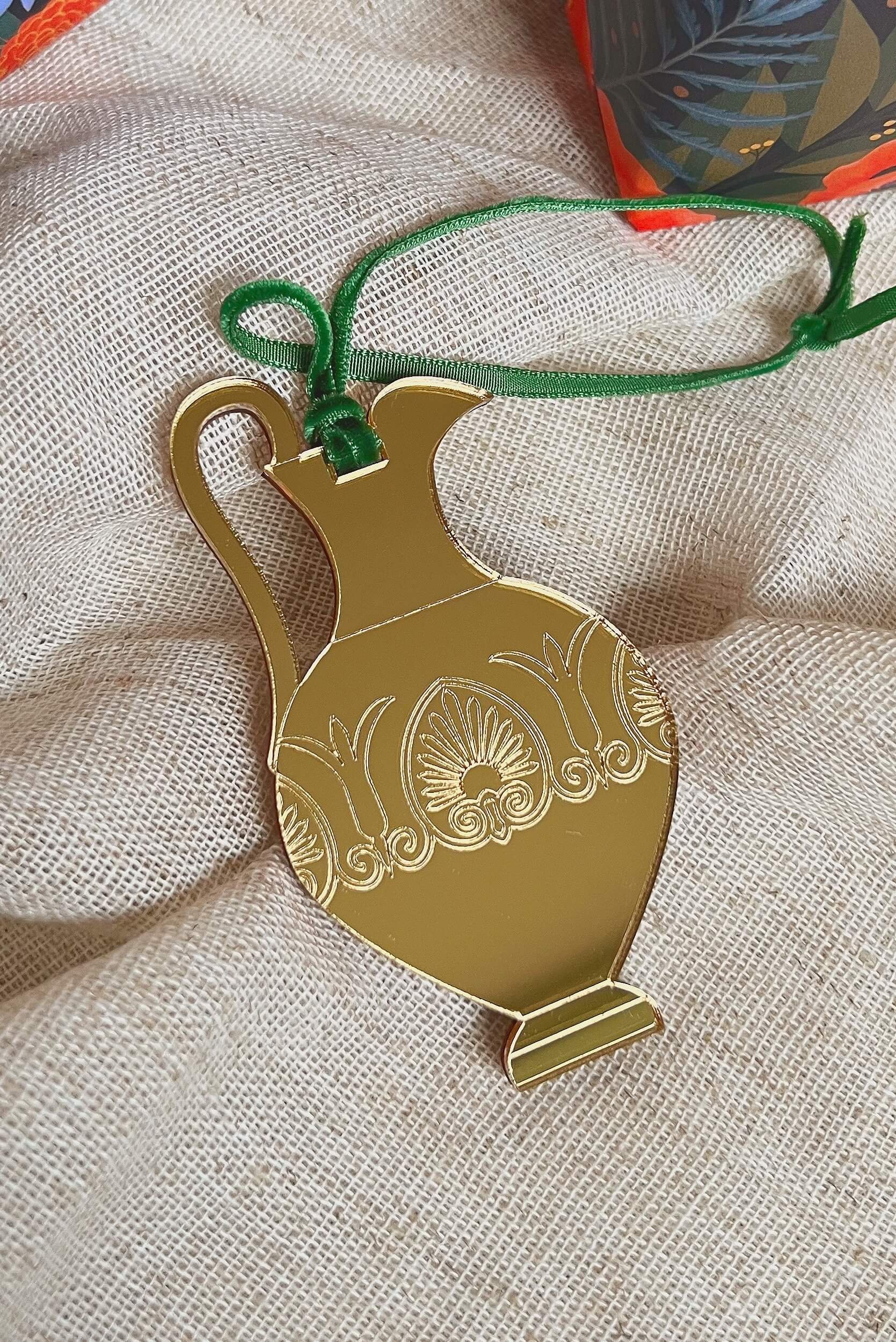 ancient greek oinochoe vase christmas tree ornament in gold mirror acrylic laid flat on neutral coloured fabric