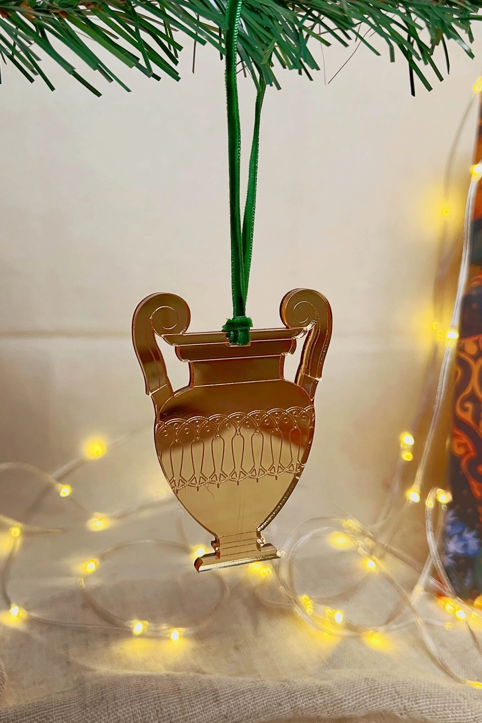 ancient greek krater christmas tree ornament in gold mirror acrylic hanging from a green velvet ribbon