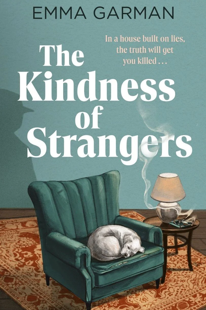 Book cover titled "The Kindness of Strangers" by Emma Garman. The cover shows a teal armchair with a sleeping white dog curled up on it, next to a small table with a smoking lamp and an ashtray, on an ornate rug. The background is teal with a large shadow of a person or object.