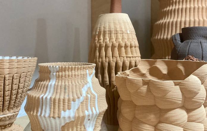 Several 3D Printed textured clay or ceramic vases and bowls in beige and brown tones displayed on a surface.