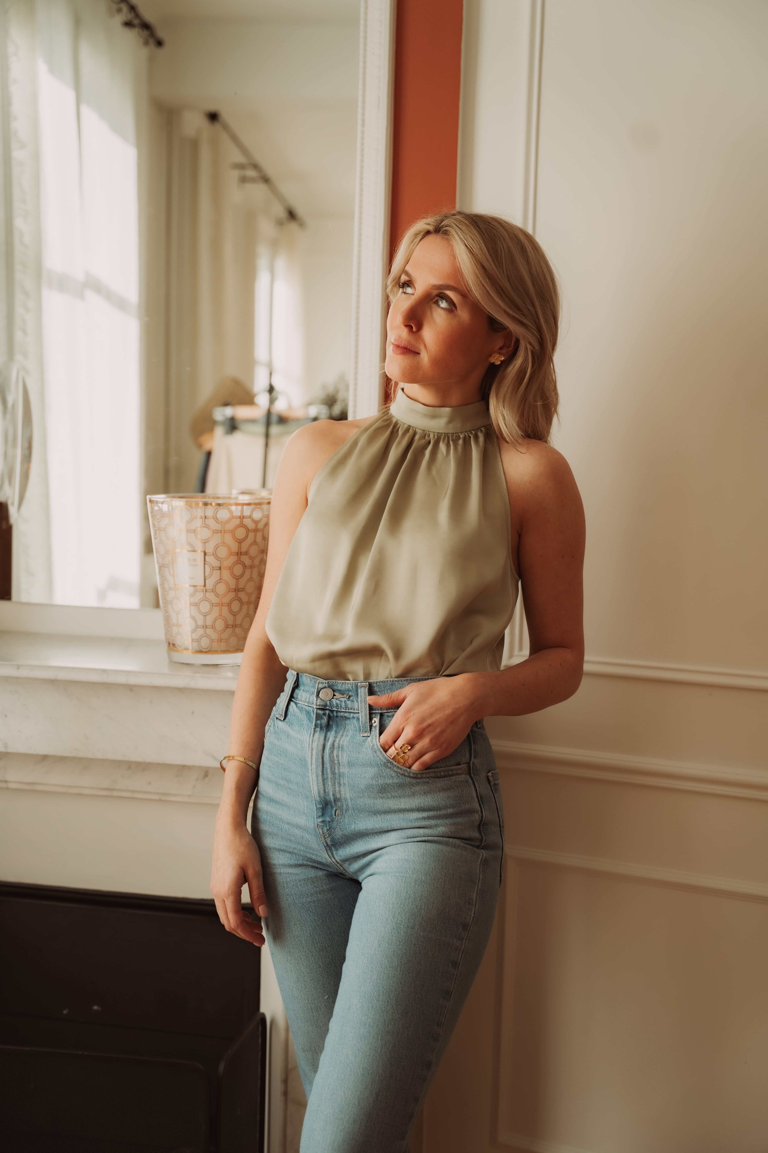 jeune femme tenue intemporelle top soyeux vert hosta avec jean dans appartement parisien