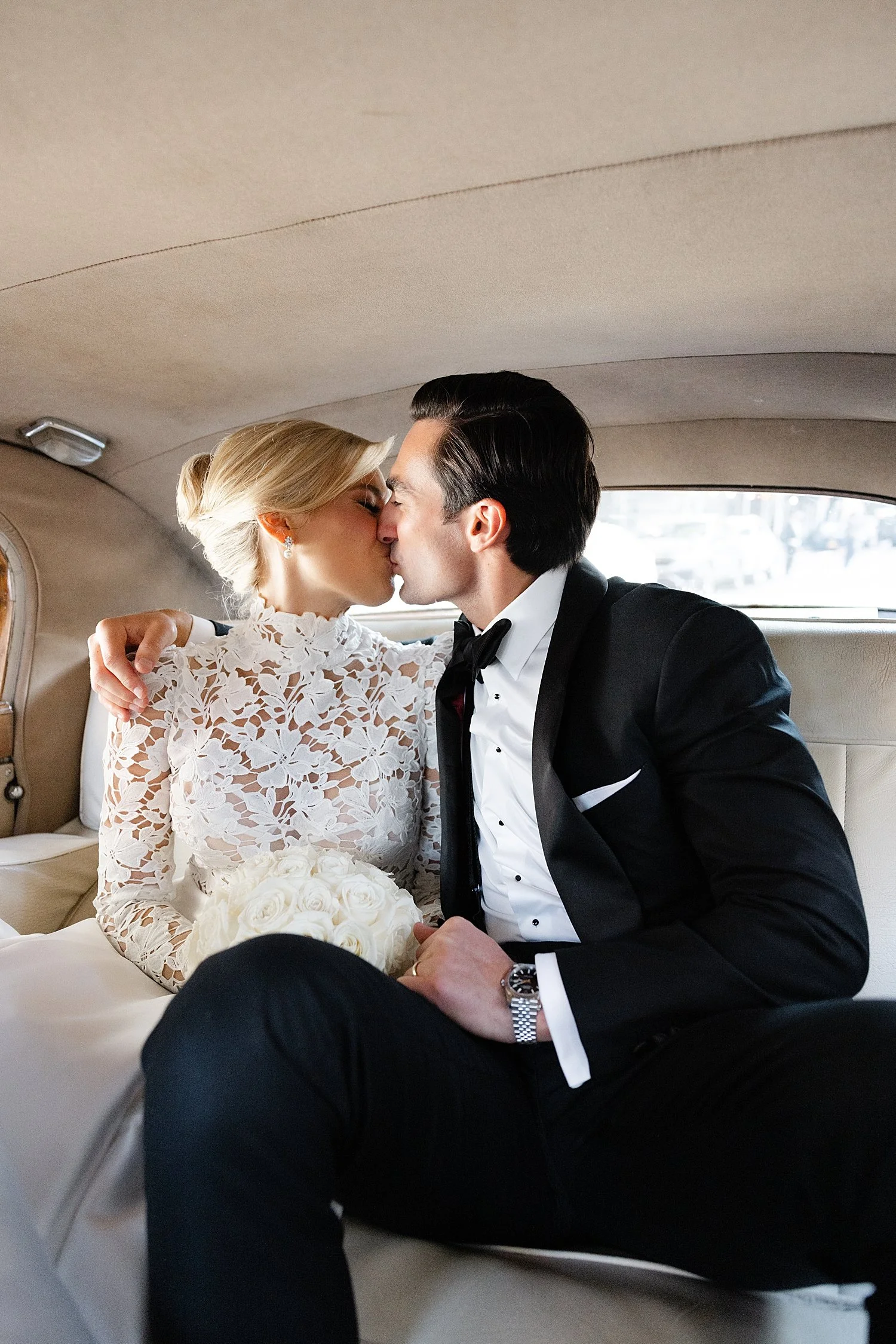  bride and groom kiss in backseat of car 