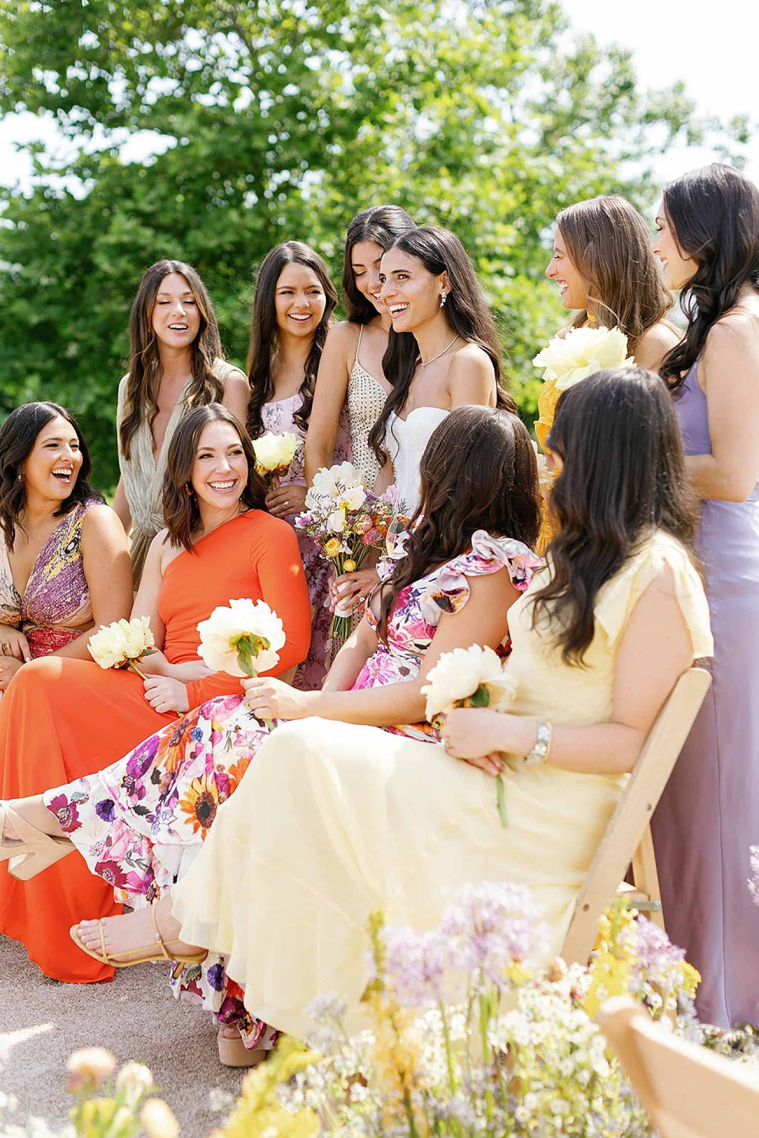  bridesmaids sit around bride wearing colorful summer dresses 