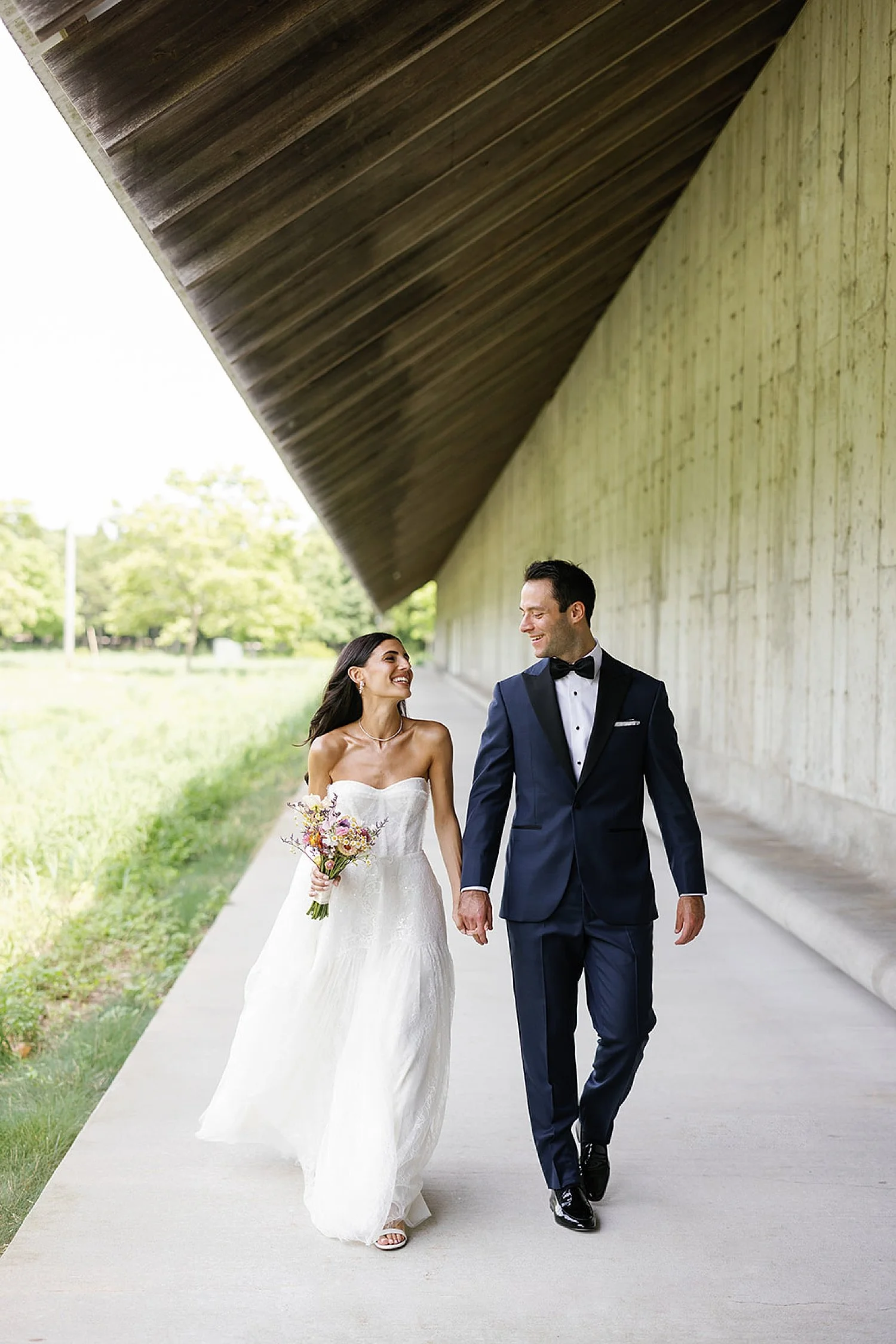  bride and groom walking together holding hands 