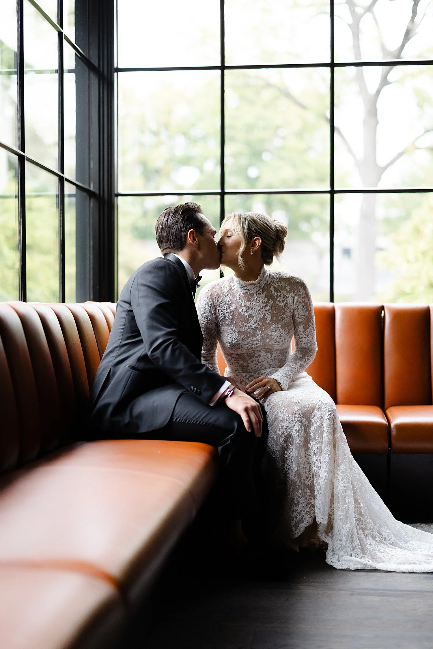  couple kiss as they sit on bench together  
