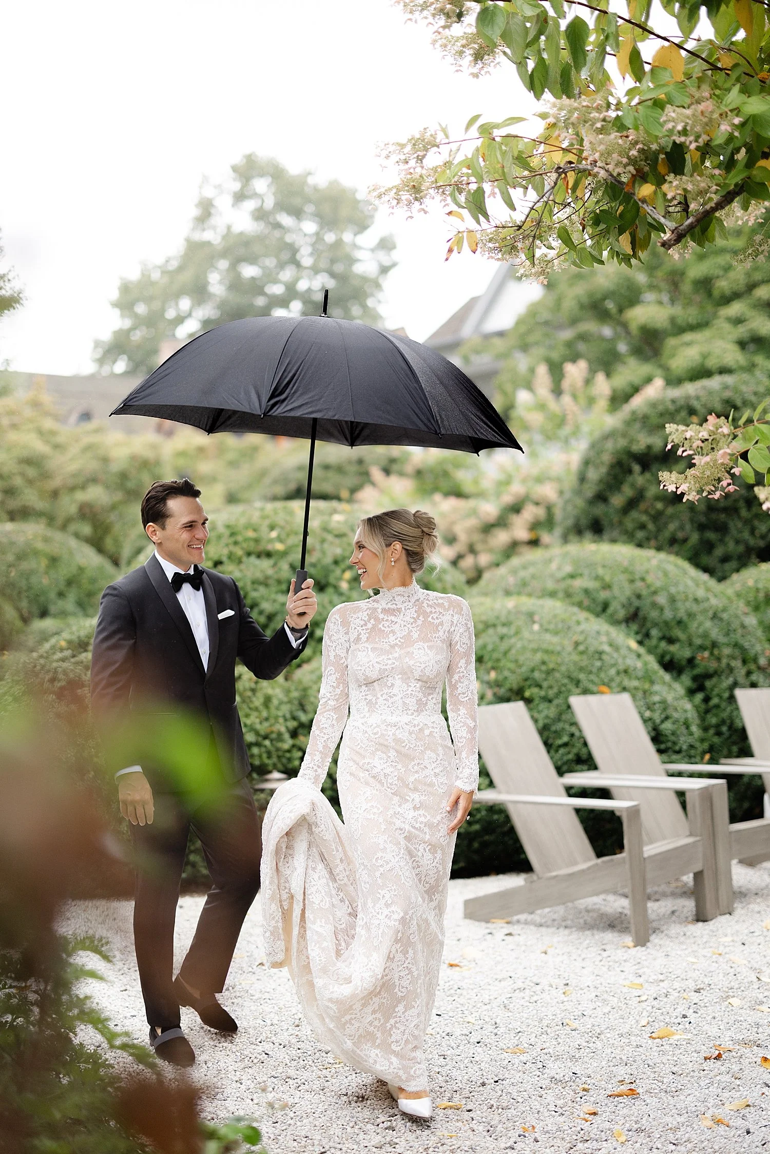  bride and groom walk together in the rain  