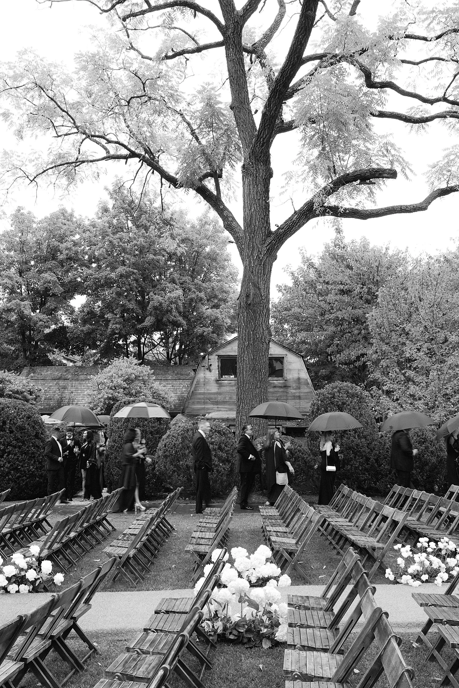  guests walking to the ceremony carrying umbrellas 