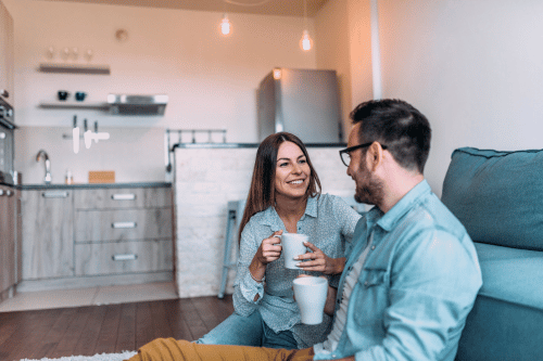 How to connect with your husband- man and woman sitting on living room floor talking and drinking coffee