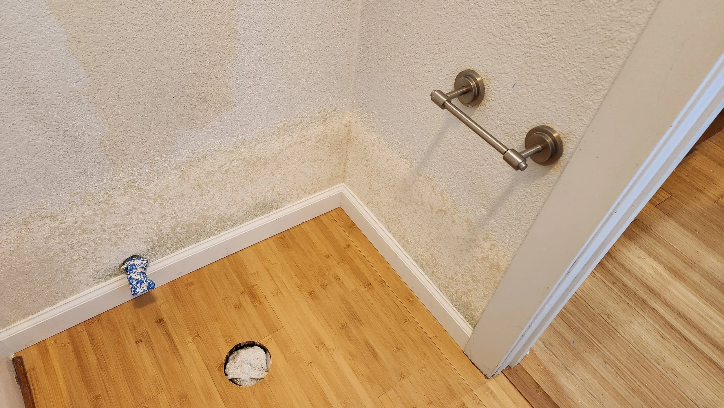 Repaired bathroom after water damage. Picture of newly textured wall, newly installed bamboo floor and new trim.
