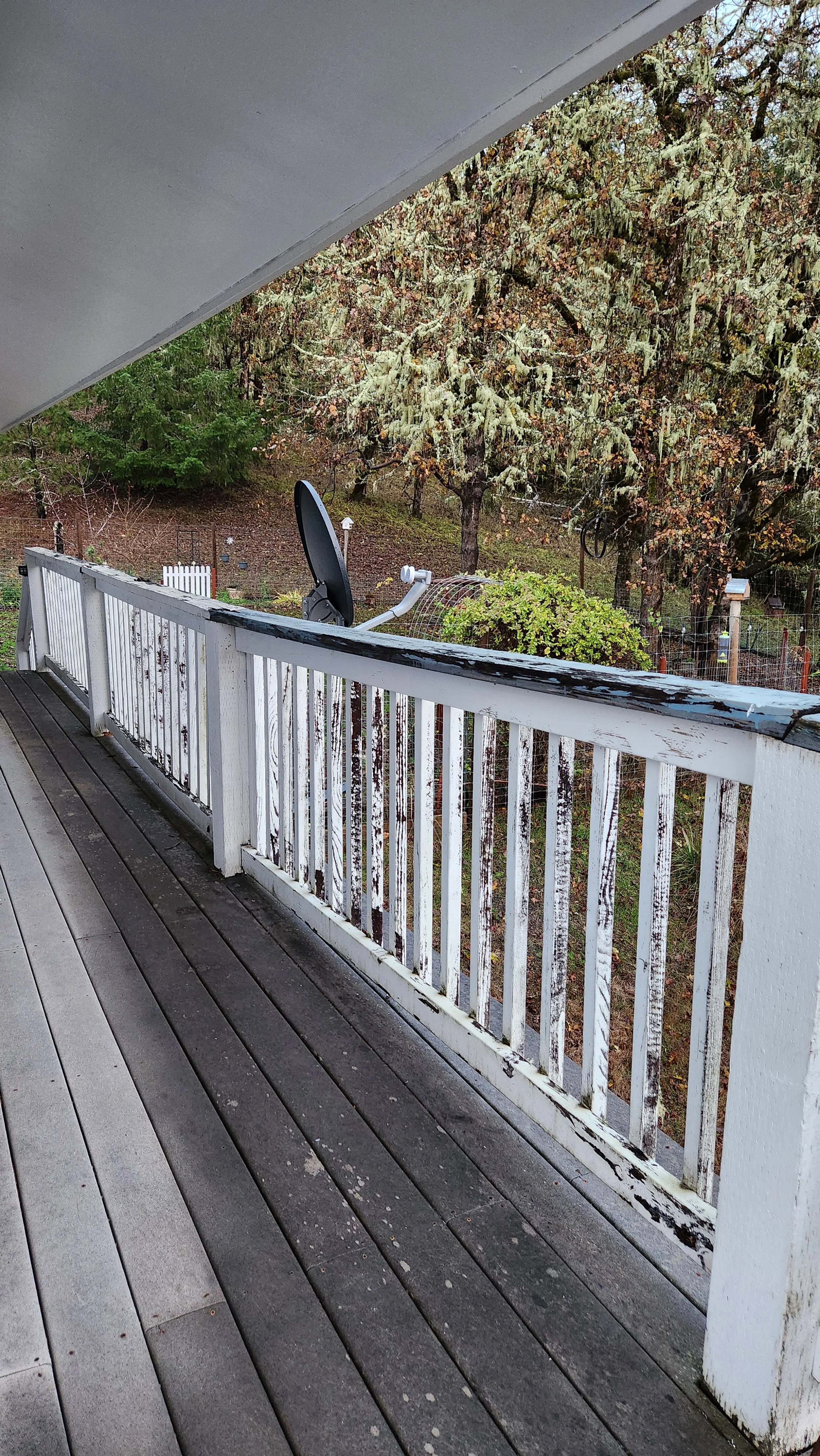 View of a wooden balcony railing with peeling white paint that needs to be repaired