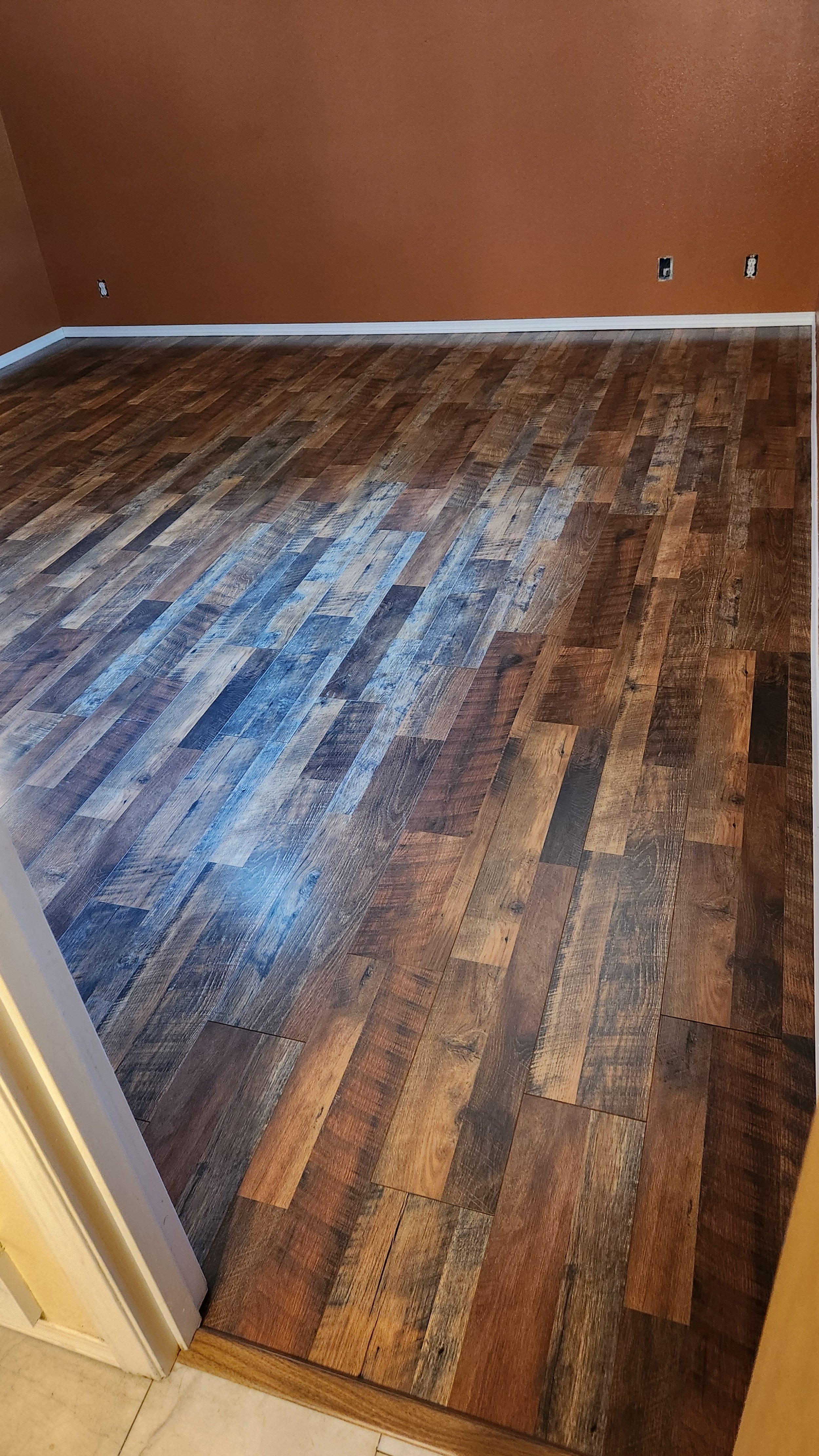 Room with newly installed hardwood flooring and orange-brown painted walls.