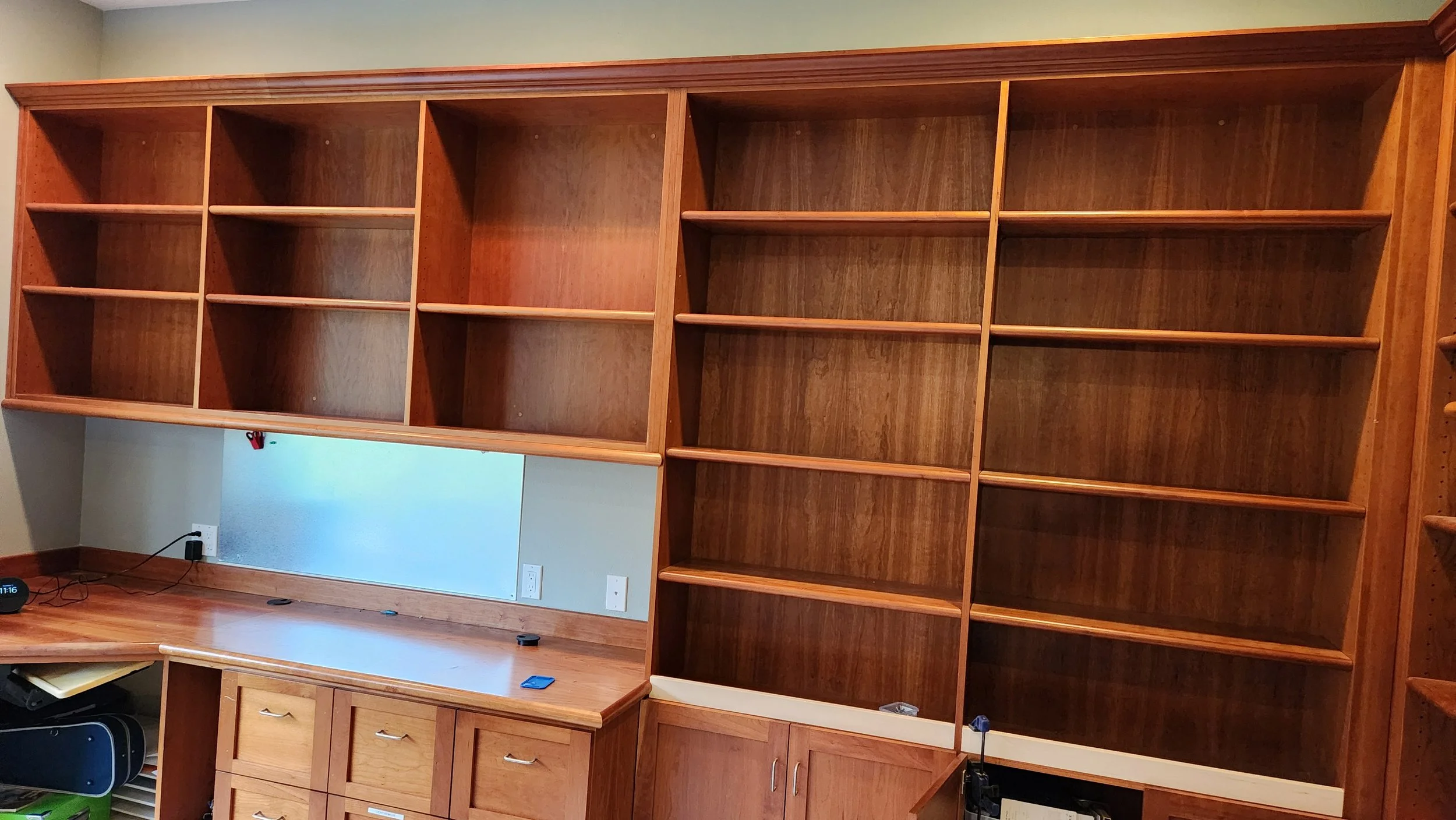 Empty wooden built-in bookshelf and desk with drawers in a room.