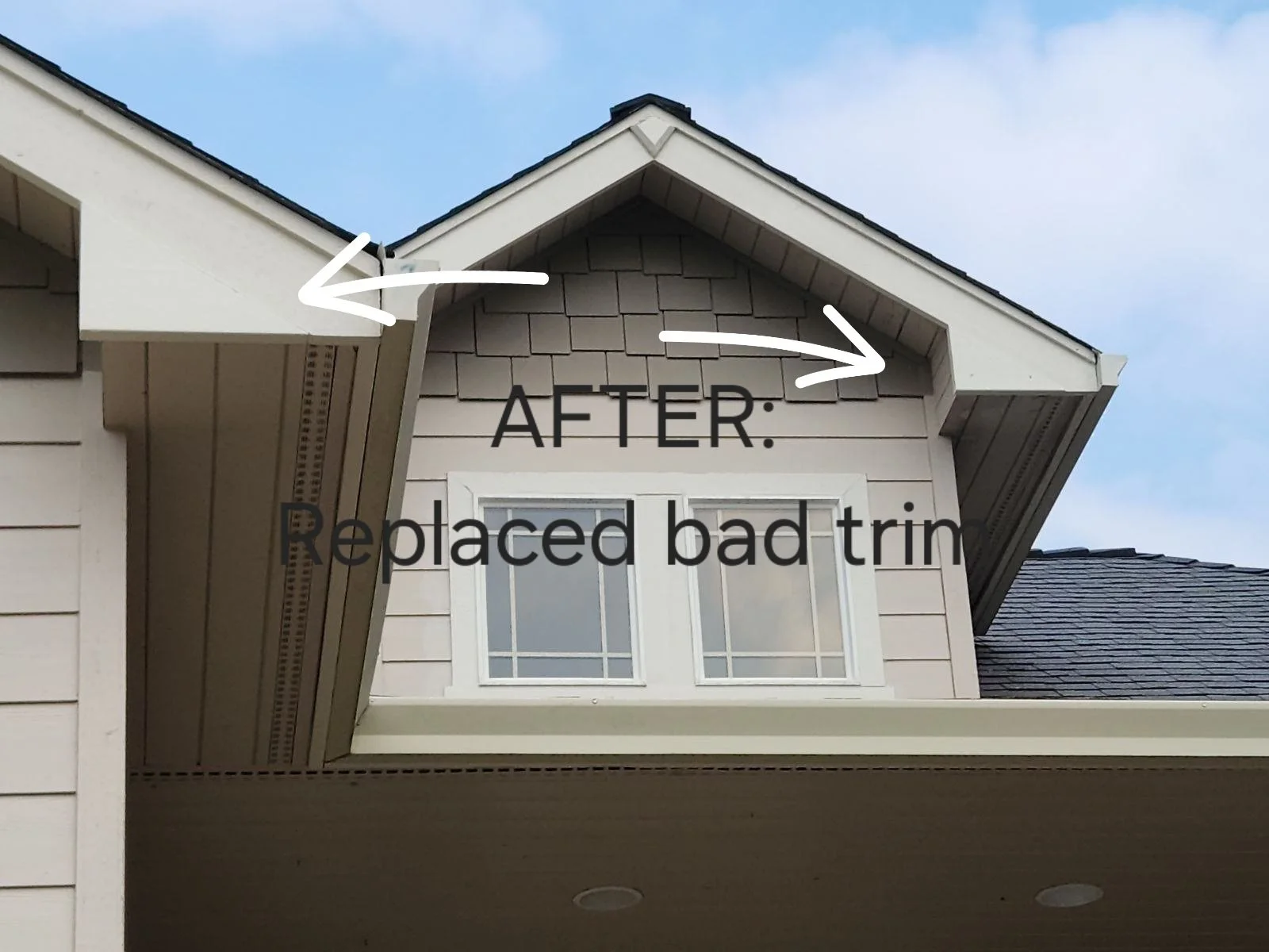 Close-up of house's exterior showing replaced trim and new molding on the roof's edge, with a window and part of the roof visible under a cloudy sky.